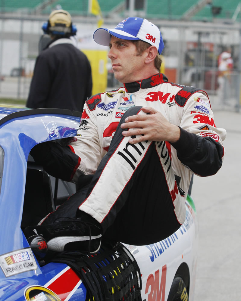 Driver Greg Biffle (16) climbs out of his race car after his qualifying run at Kansas Speedway.