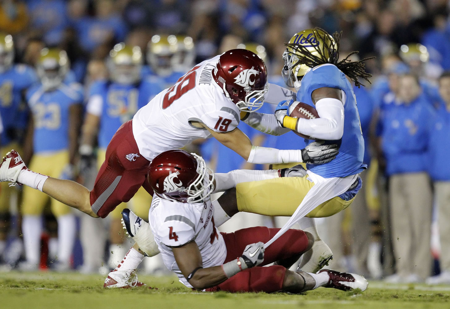 UCLA wide receiver Josh Smith, right, is tackled by Washington State safety Jordan Simone (19) and safety Anthony Carpenter (4) during the first half Saturday.