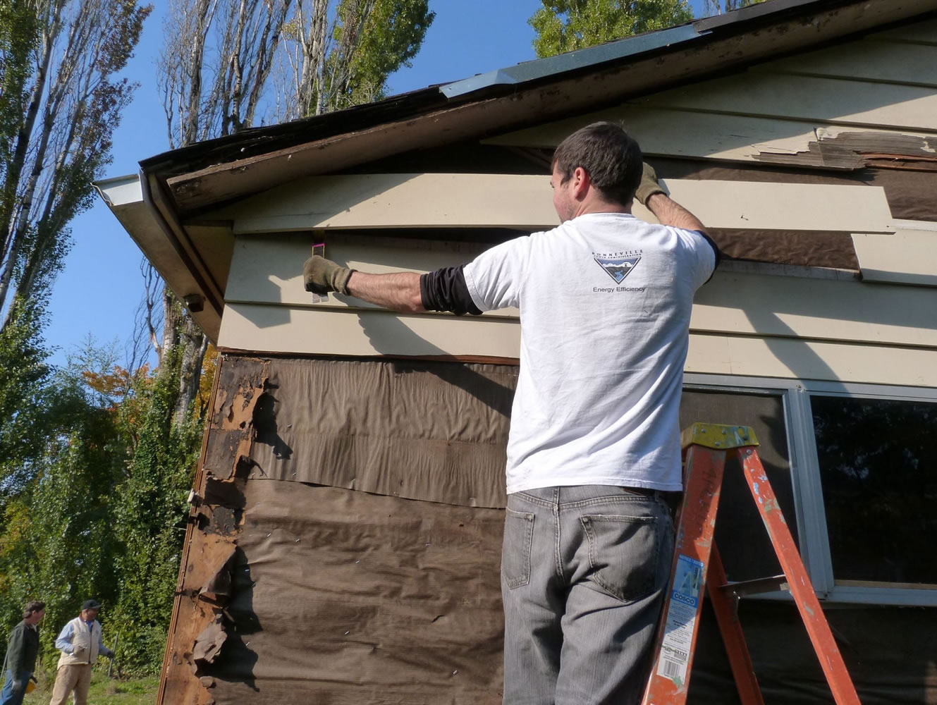 Bagley Downs: Bonneville Power Administration energy efficiency specialist Rick Hodges removes old siding from a home during a volunteer weatherization day event.