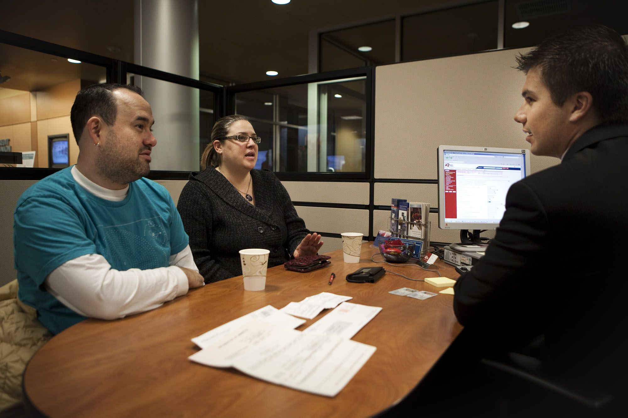 Dan Boggs, member service officer at iQ Credit Union, helps Liz and Jesse Weiss open a checking account. The couple previously banked at Bank of America but were fed up with fees.