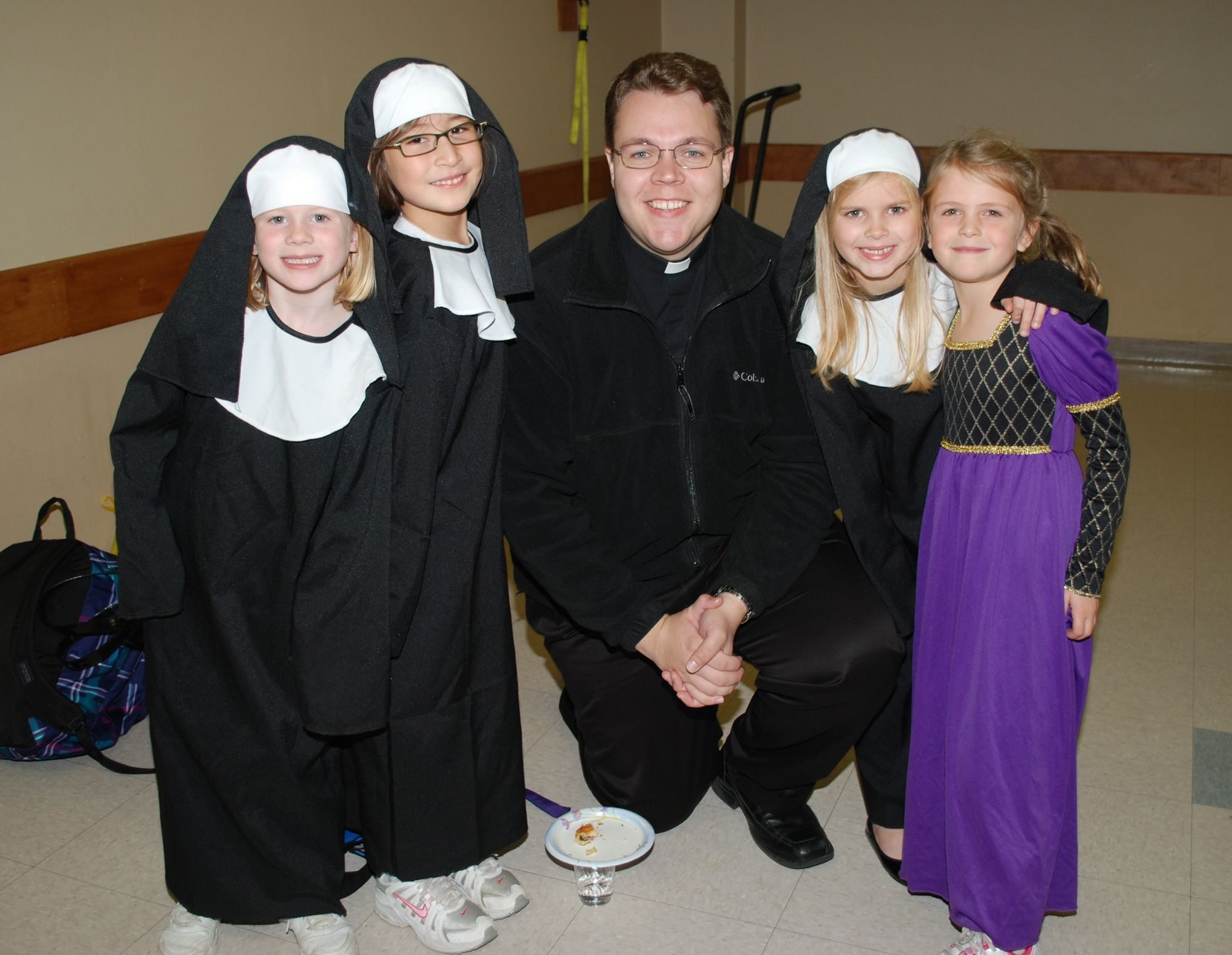 The Rev. Matthew Oakland visits with the mini-saints of Pacific Crest Academy. From left are: Campbell Deringer as St. Rose of Lima; Jane Brotherton at St. Jane; Hannah Jo Hammerstrom as St. Clare; and Anna Mooney as St.