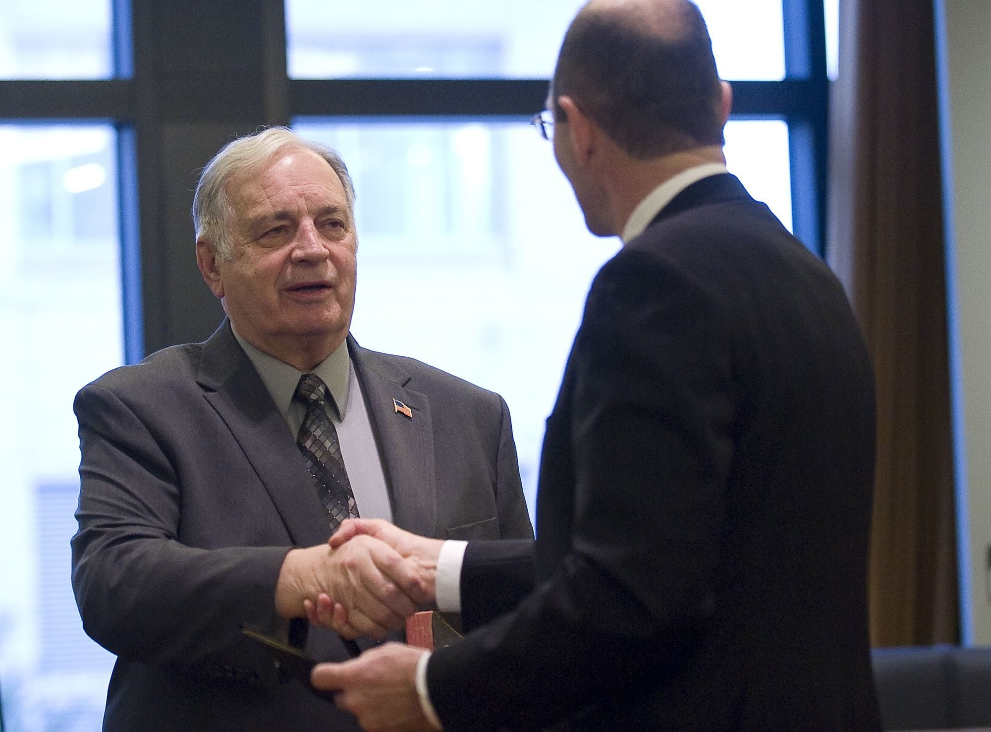New City Councilor Bill Turlay shakes hands with County Auditor Greg Kimsey after he was sworn in at at City Hall on Thursday morning.