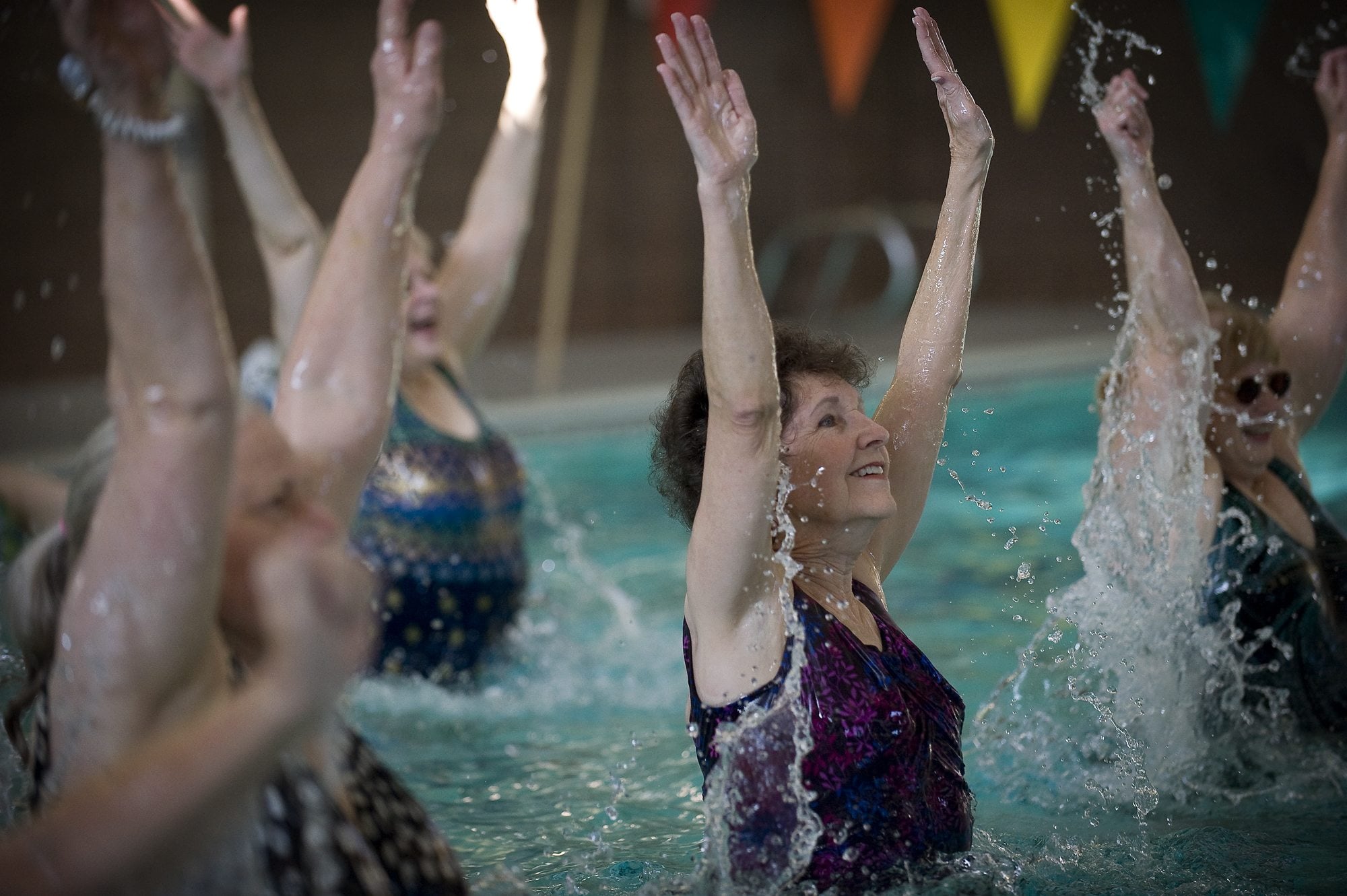 Cathy Harper, center, leaps out of the water during an aqua Zumba class at the Touchmark Health and Fitness Club in east Vancouver.