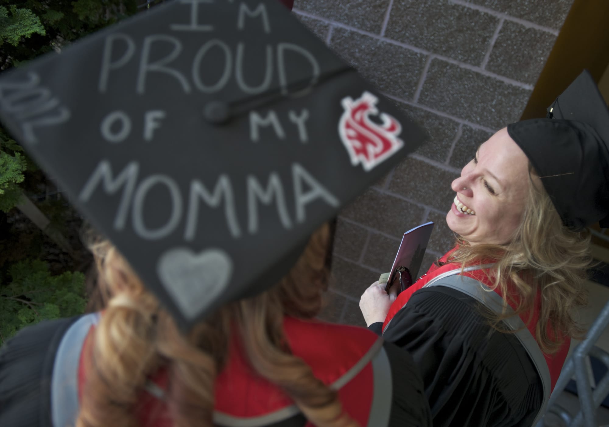 Cori Jones' mortarboard makes it clear how she feels  about her mother, Cheryl, right. Both women graduated Saturday from Washington State University Vancouver.