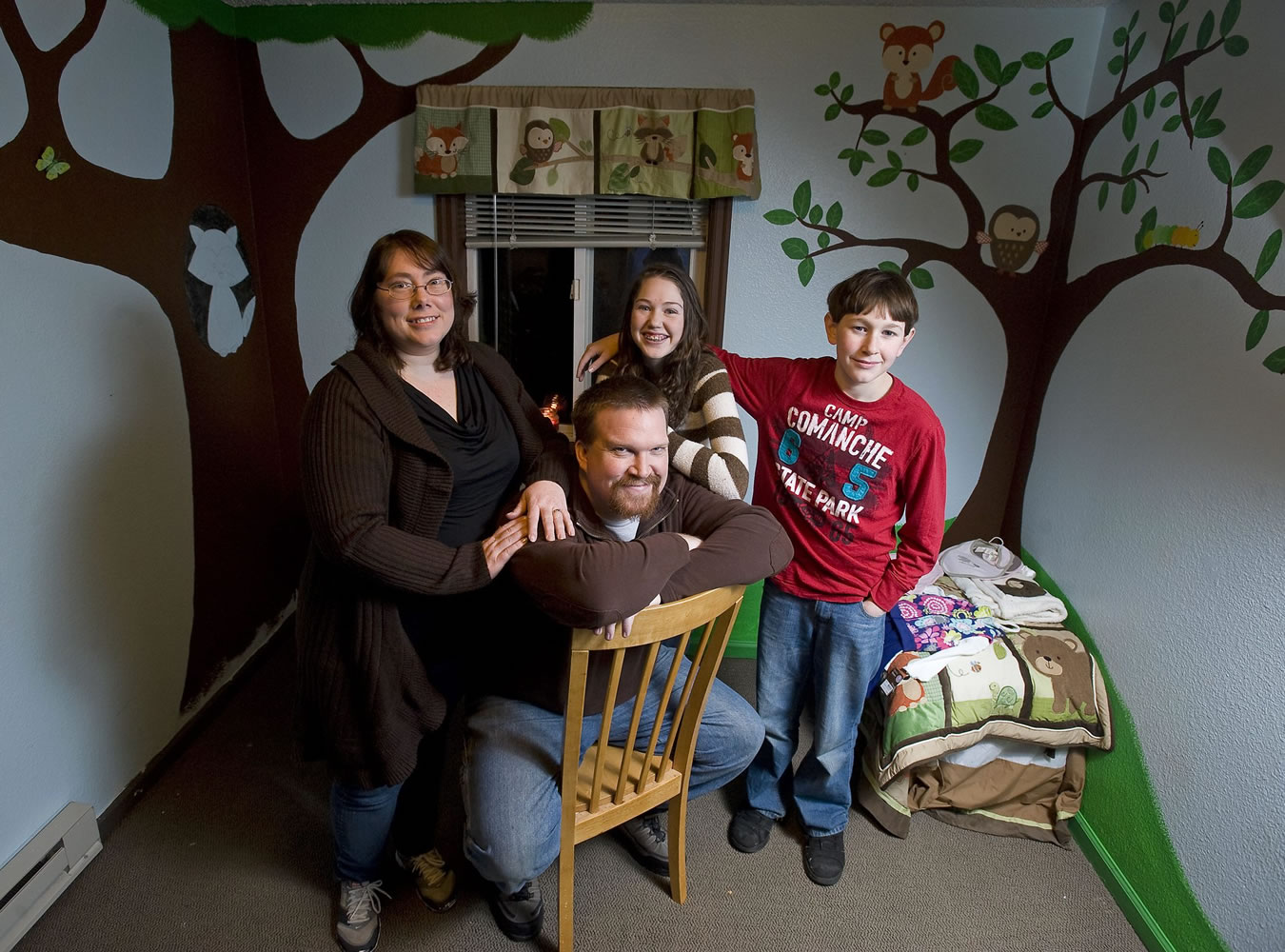 Mark and Rebecca Jenks pose for a portrait with Rebecca's children, Tamara Emler, 15, and Brandon Emler, 13, inside a room prepared for their adopted baby.
