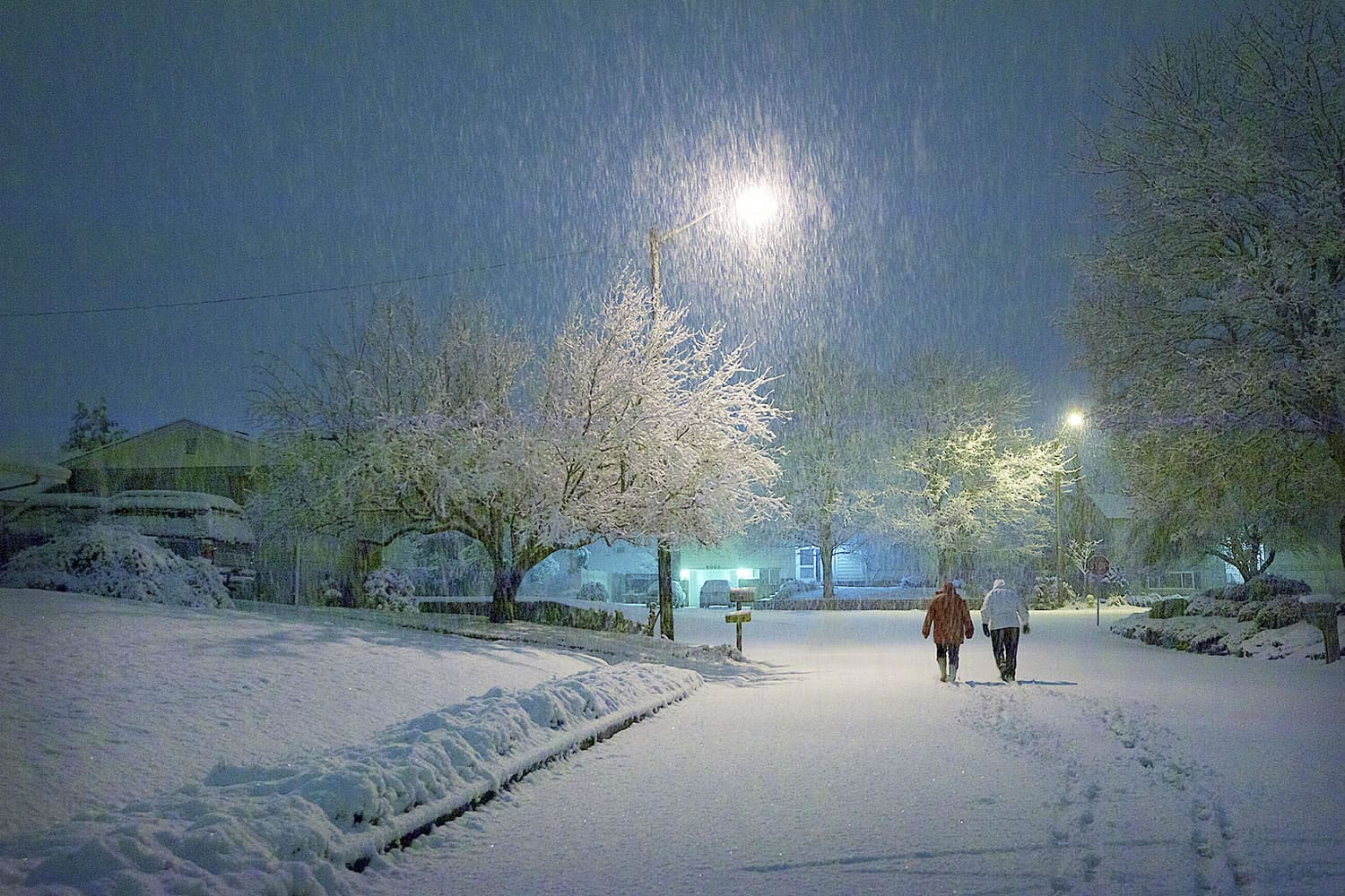 A winter snowstorm inspires Northwest neighborhood residents to take an early-morning walk Wednesday in Vancouver.
