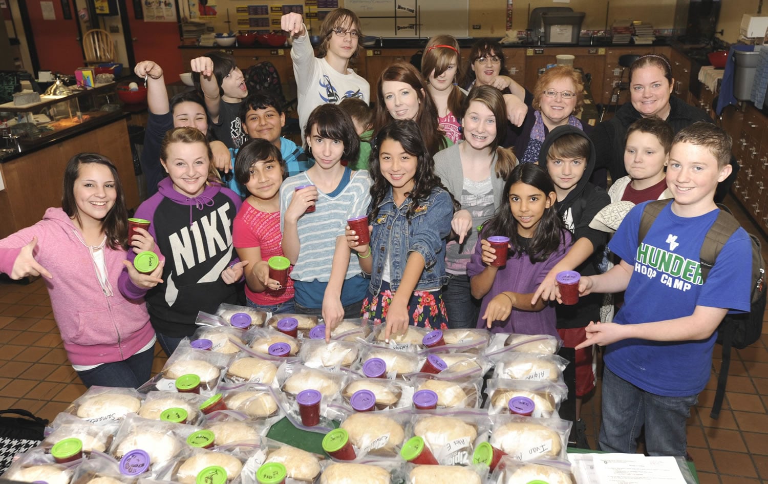 Teacher Erin Lark, top center, and her class show off their freshly made bread dough and jam Monday at Wy'east Middle School in Vancouver.