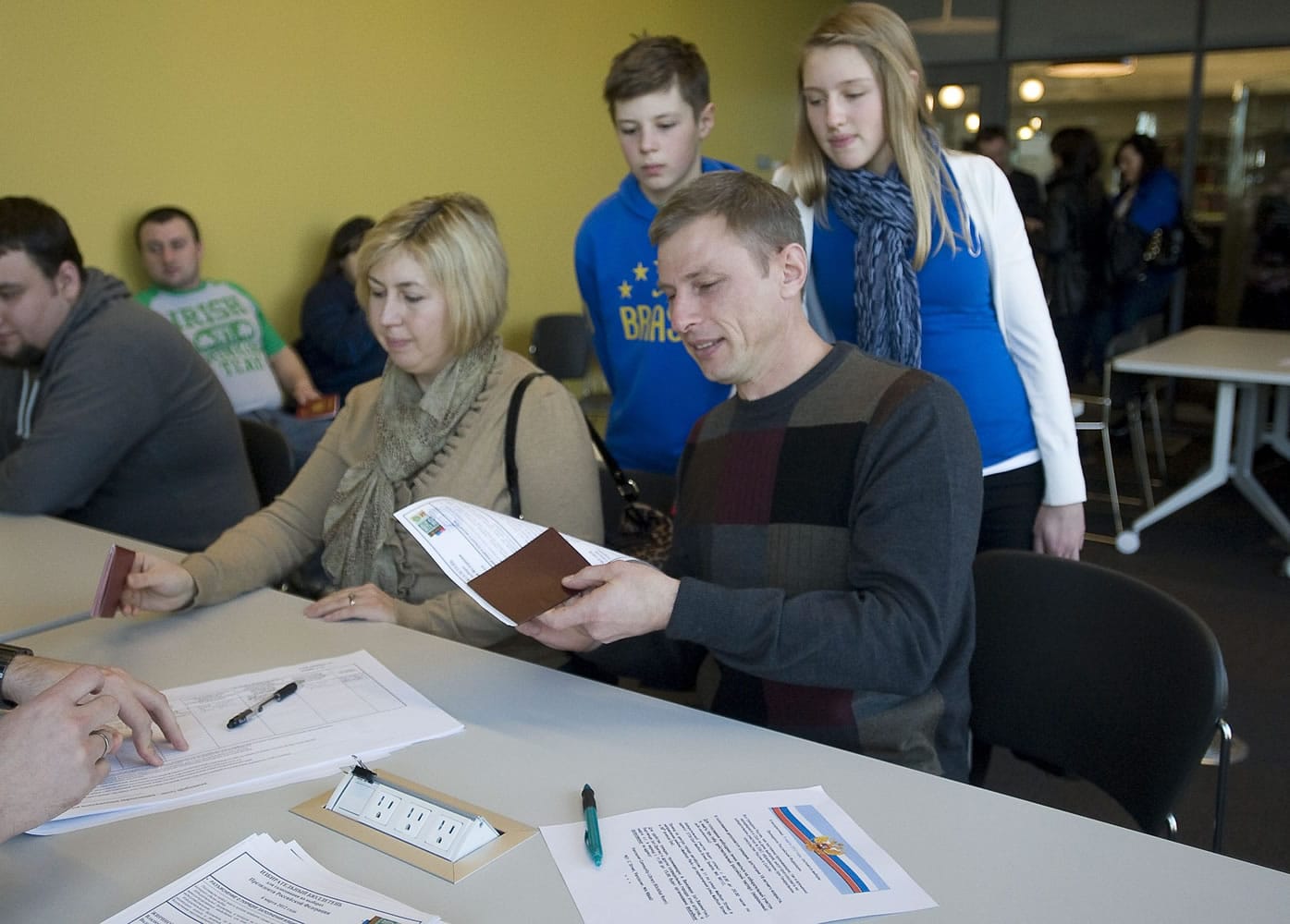 Russian citizens Olga and Andrey Dolbinin, of Vancouver have their information processed before casting their votes in the Russian presidential election on Sunday in the Vancouver Community Library's Klickitat Room. Their children Maksim, 12, and Irina, 15, look on.