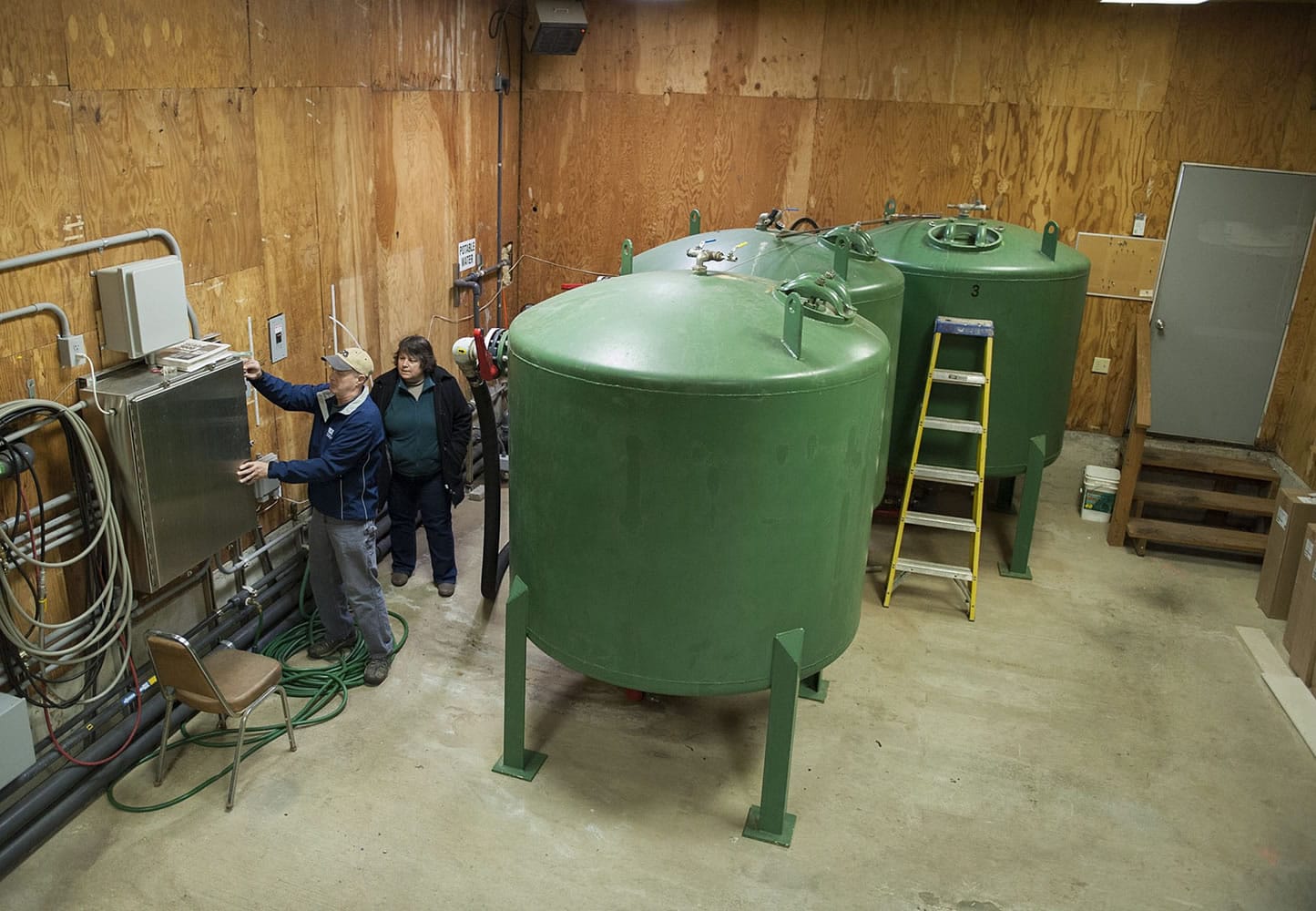 Richard Read, senior environmental scientist for EA Engineering, Science and Technology Inc., left, joins Judy Smith of the Environmental Protection Agency as they check out the ion exchange system that removes hexavalent chromium from water Friday in Hazel Dell.