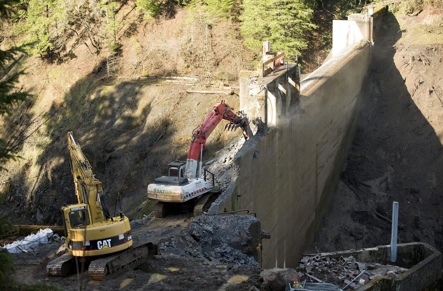 Photos by Steven Lane/The Columbian
The process of removing Condit Dam continued Friday as crews used heavy machinery to chip away at the concrete structure.  Top: Crews use heavy machinery to move sediment built up over a century into the White Salmon River, speeding the flushing process and stabilizing the bank.