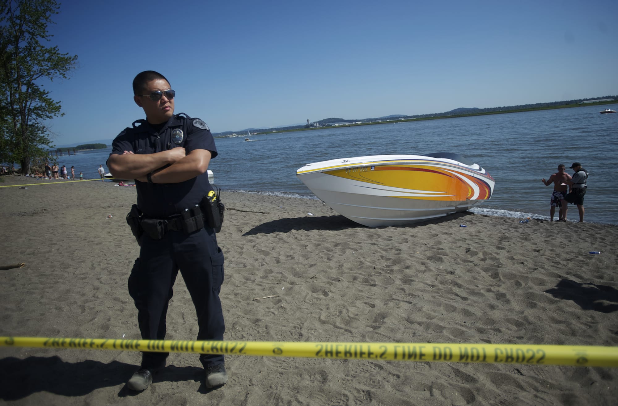 A Vancouver Police officer watches a tape line as others investigate a boating accident at Wintler Park on Saturday.