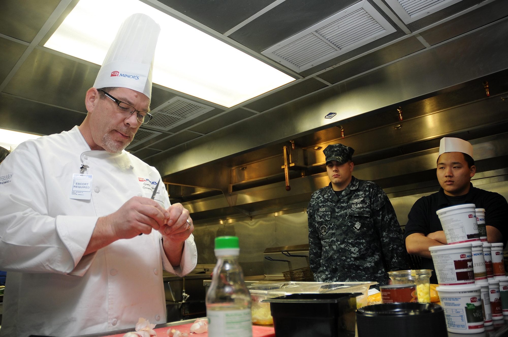 Vancouver: Corporate Executive Chef Greg A. Taylor, from Vancouver, peels garlic while demonstrating food service skills for sailors assigned to the aircraft carrier USS Ronald Reagan in the galley of barge APL-62.