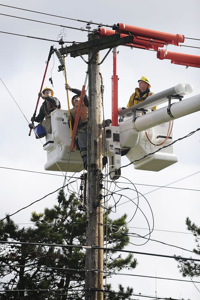 Clark Public Utilities linemen Kenny Cudd, from left, Tommy Jensen and Zach Muonio move conductors as they prepare to replace a power pole in use since 1956.