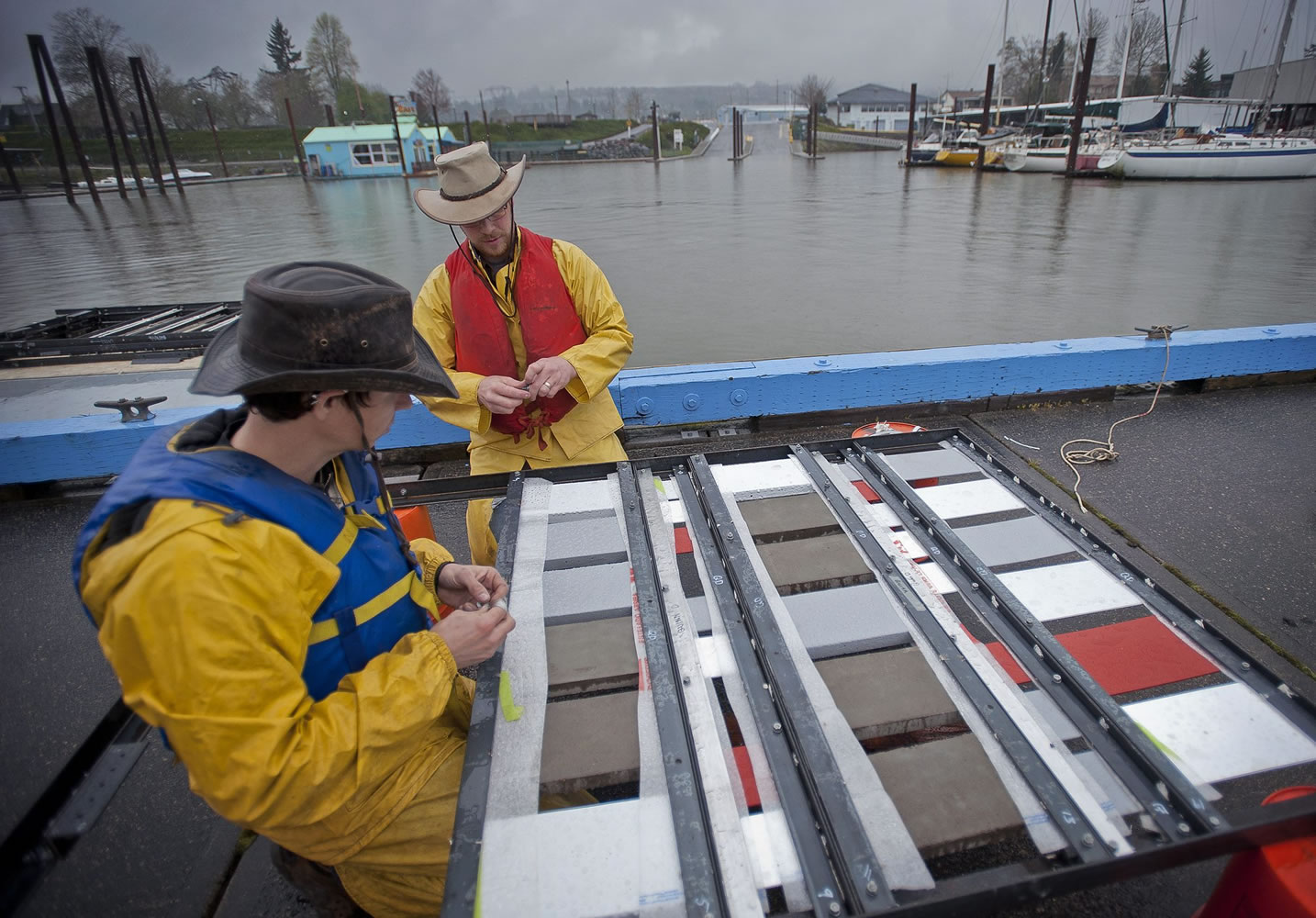 Steve Wells, right, a Portland State University research assistant, and PSU student Leonard Caldwell attach treated tiles to a metal frame that will be submerged and fastened to a dock at the Port of Camas-Washougal.