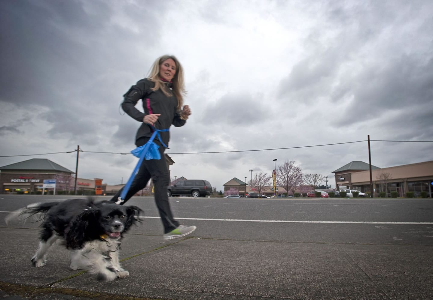 Teri Wilson runs with her 15-month-old Cavalier King Charles spaniel, Luna, on Northeast 99th Street on Wednesday. Luna had a severely broken leg when she was rescued from a home.