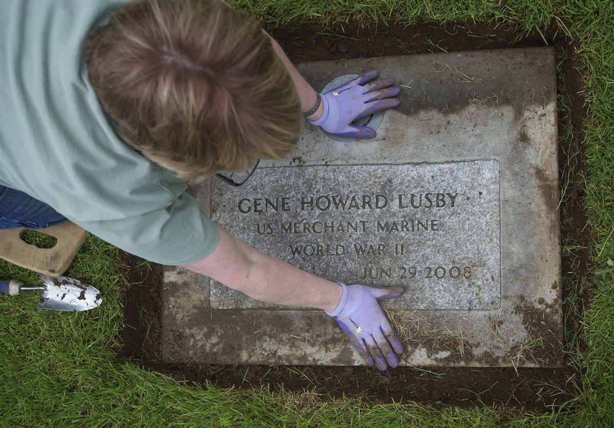 Sharron Wannmaker tends to the gravestone of her dad, Gene Lusby, at Park Hill Cemetery on Sunday.