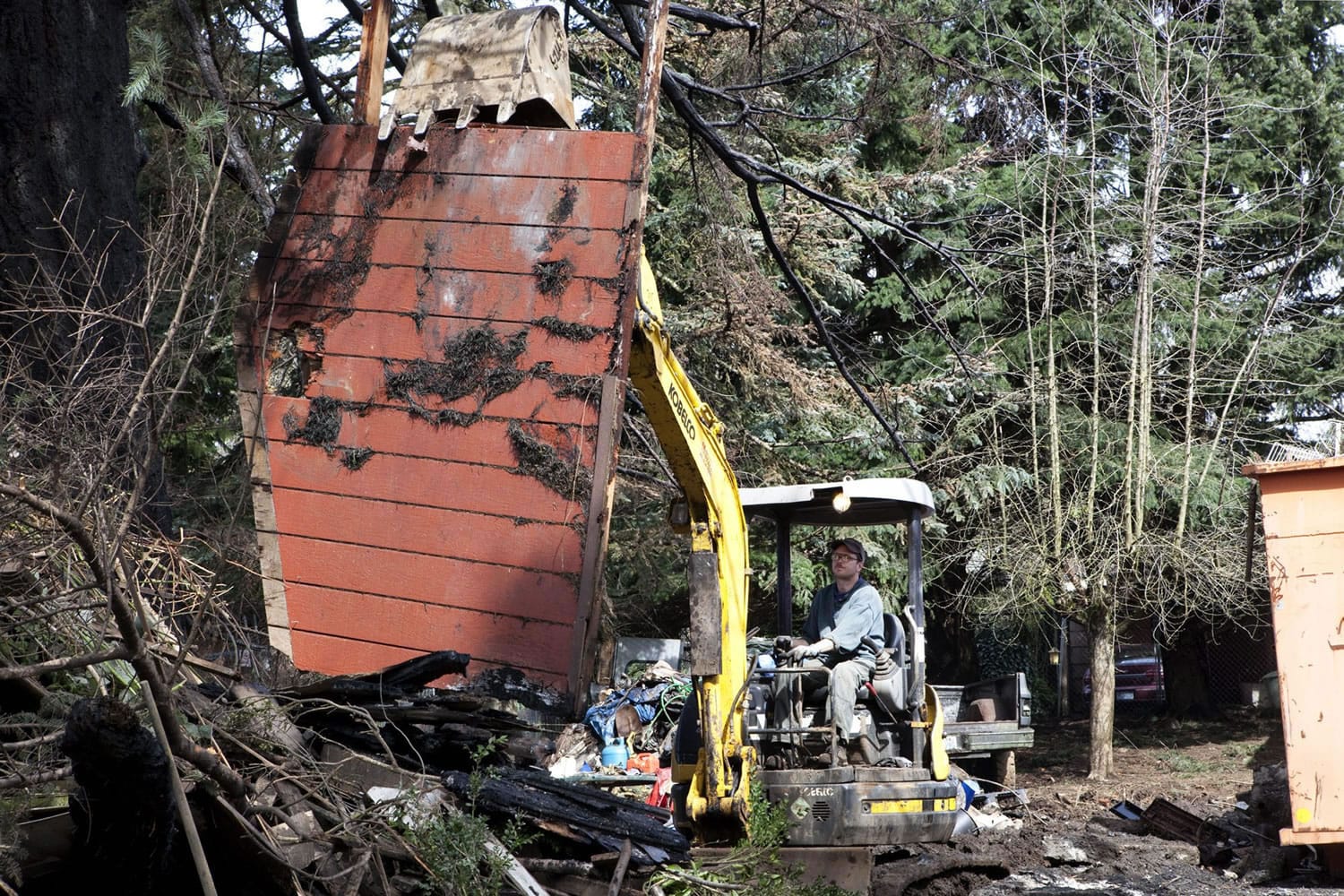 An excavator Monday morning removes burned debris from Steven Stanbary's property on F Place in Washougal. Stanbary killed himself, his wife and her twin sister Dec.