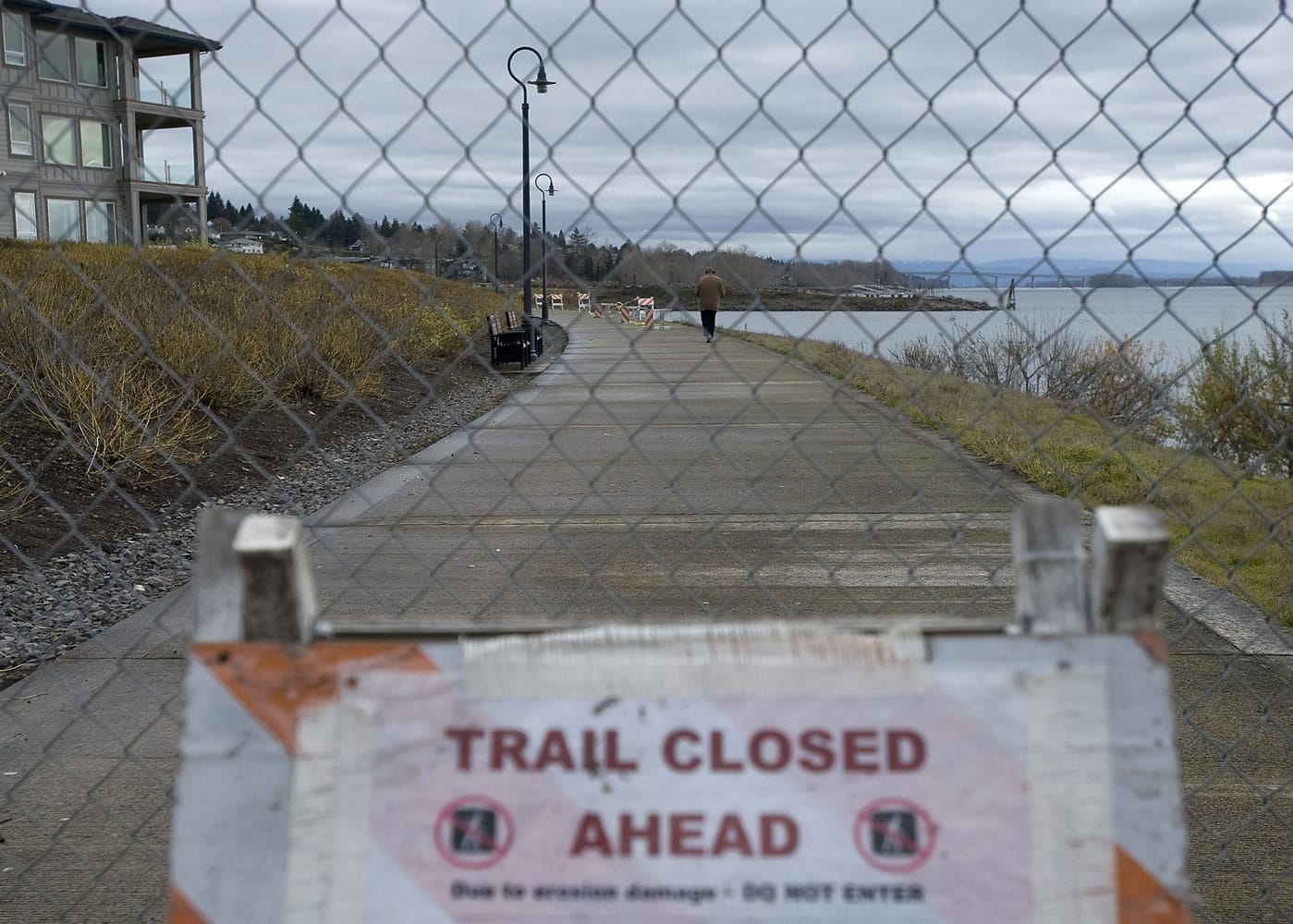 A man walks along a closed portion of the Renaissance Trail near the Tidewater Cove Condominiums on Tuesday.