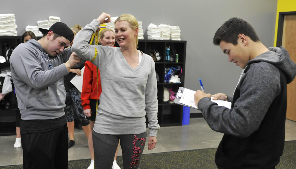 Sean Hibbard, left, and Josh Hibbard, right, take measurements for Jadine Juarez as she begins an eight-week nutrition program Tuesday at Results Fitness Training in Camas. The new fitness facility offers group TRX, yoga and Pilates classes, as well as the nutrition program.