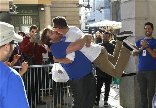 A customer jumps into the arms of an Apple employee outside the Apple Store in Covent Garden, to celebrate his purchase of the new iPhone 4S, which went on sale in London, Friday, Oct. 14, 2011.