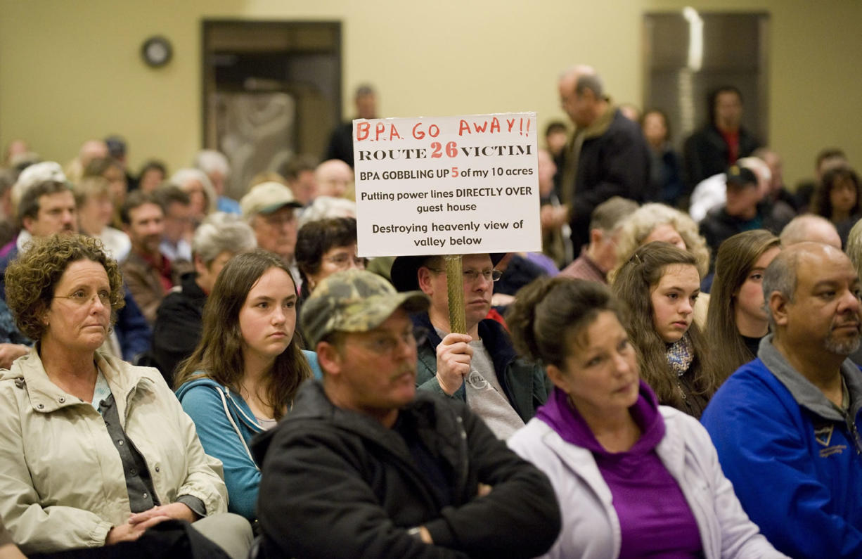 A property owner holds a sign criticizing one of several possible 500-kilovolt power line routes being considered by the Bonneville Power Administration during a listening forum at the Battle Ground Community Center on Dec.