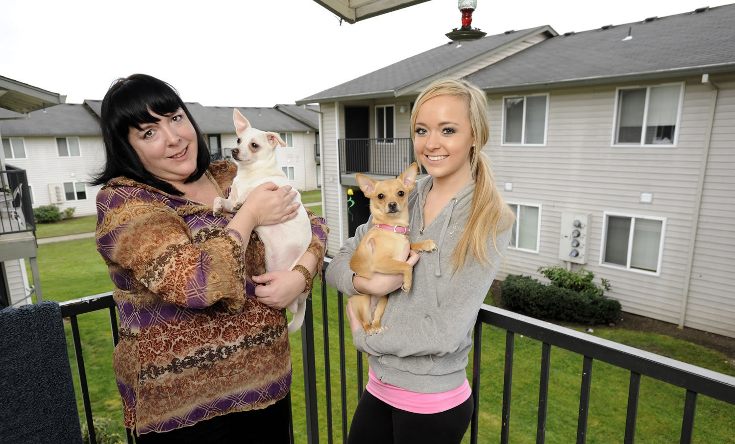 Michelle McLaughlin, left, with Lucky, stands with her daughter, Cora Hall, with Riley, on the balcony of their Orchards-area apartment.