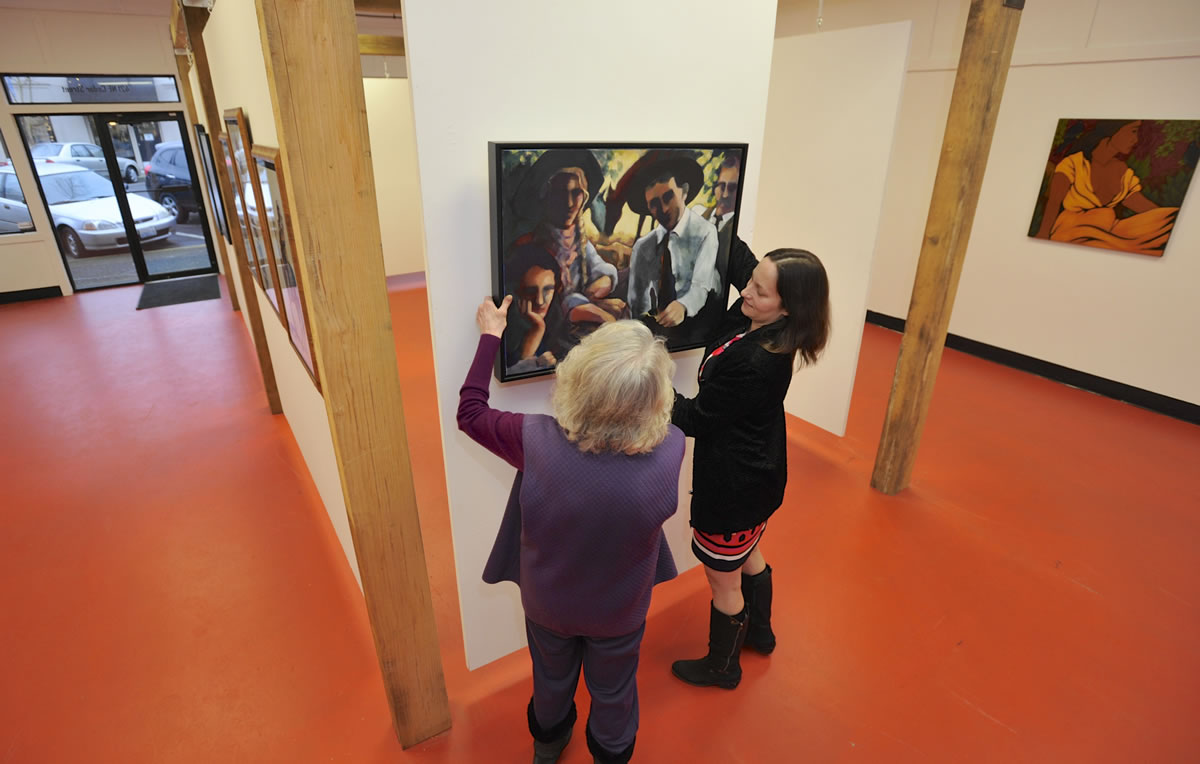 Diana Faville, left, and Maria Gonser hang a work by Sandra Jones Campbell at the Attic Gallery&#039;s new location in Camas.