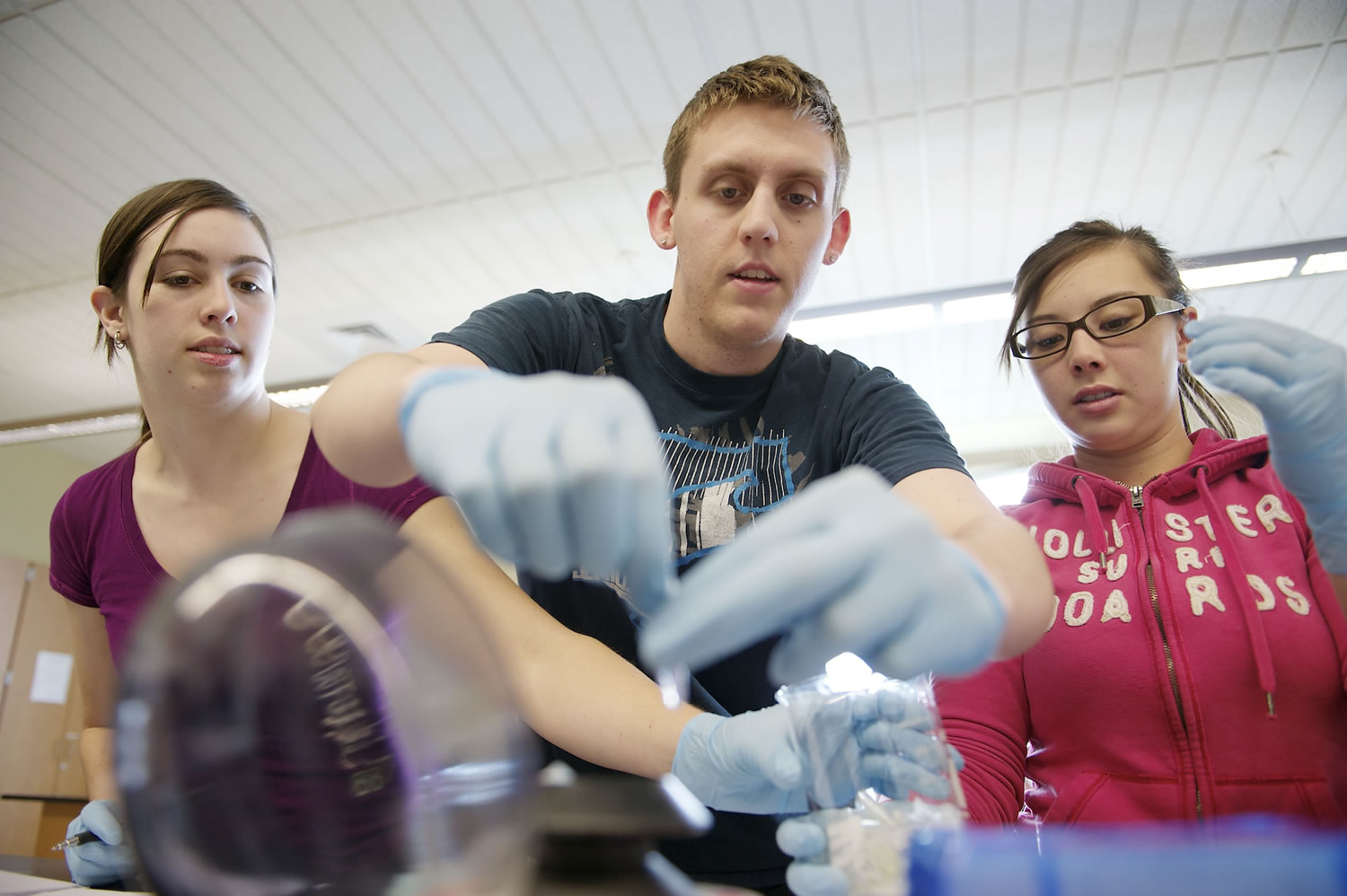 Yvette Leggewie, from left, Jonathan Clement and Katie Martin, use a centrifuge to isolate an antibiotic that fights a wheat-killing fungus.