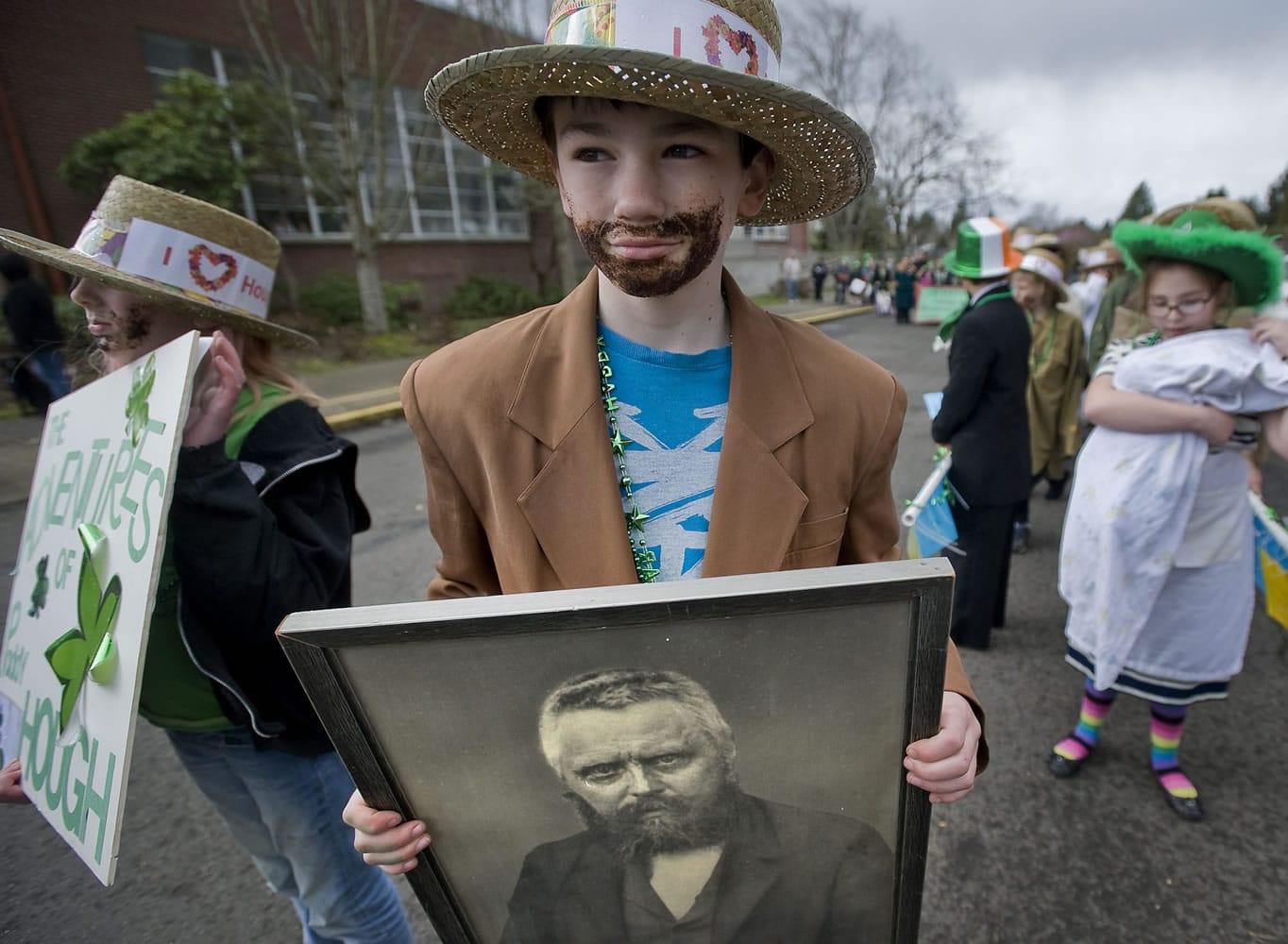 Kellen Larsen, 10, holds a portrait of Paddy Hough as he lines up with other fifth-graders from Mina Milligan's class at Hough Elementary before the start of Friday's annual parade.