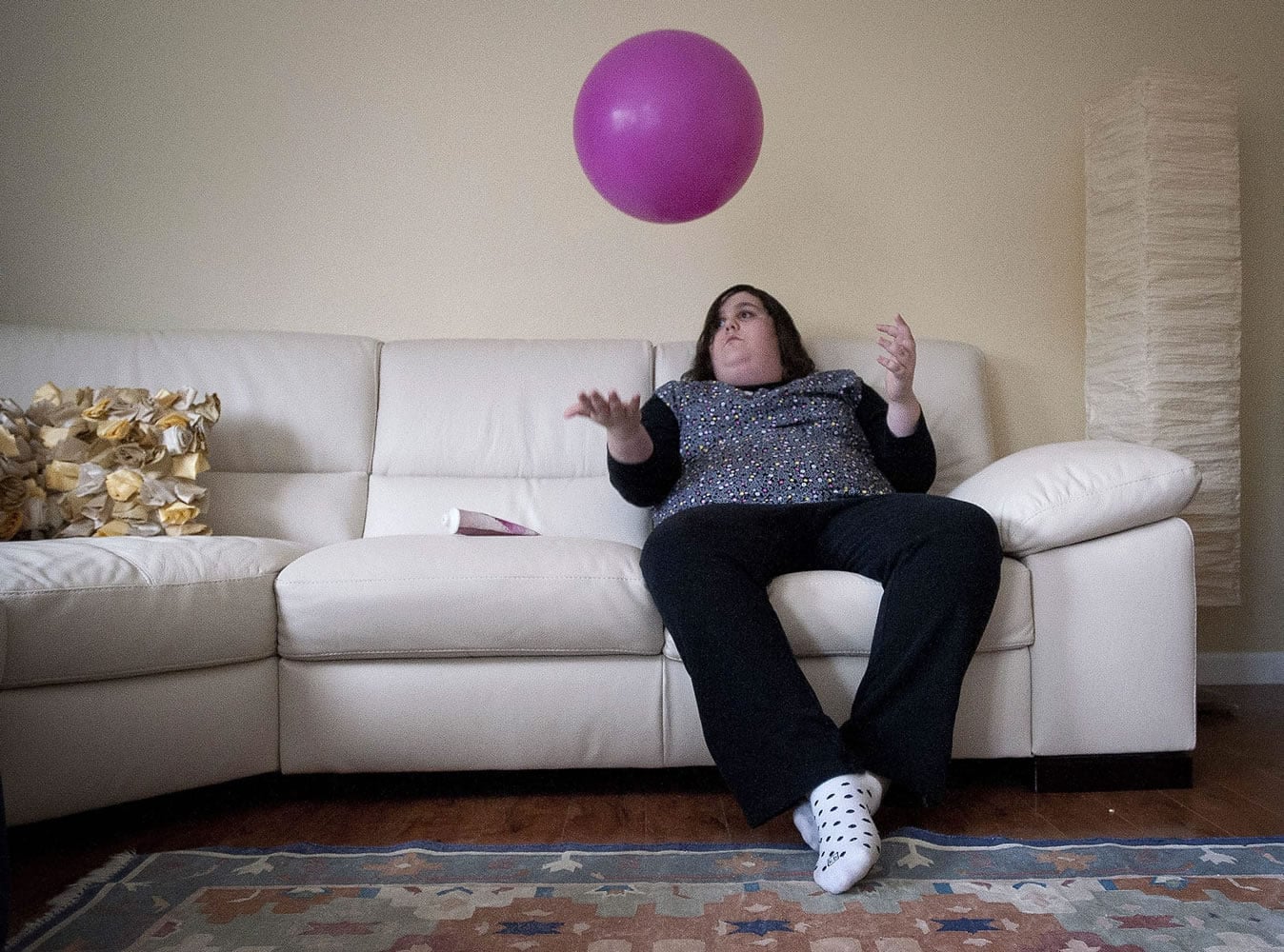 Anna Rolfe plays with a ball Friday while on the couch at her home.