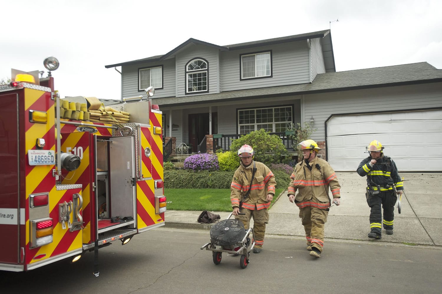 A firefighter wheels out a fan used Wednesday evening to ventilate the site of a fire at 5525 N.W.