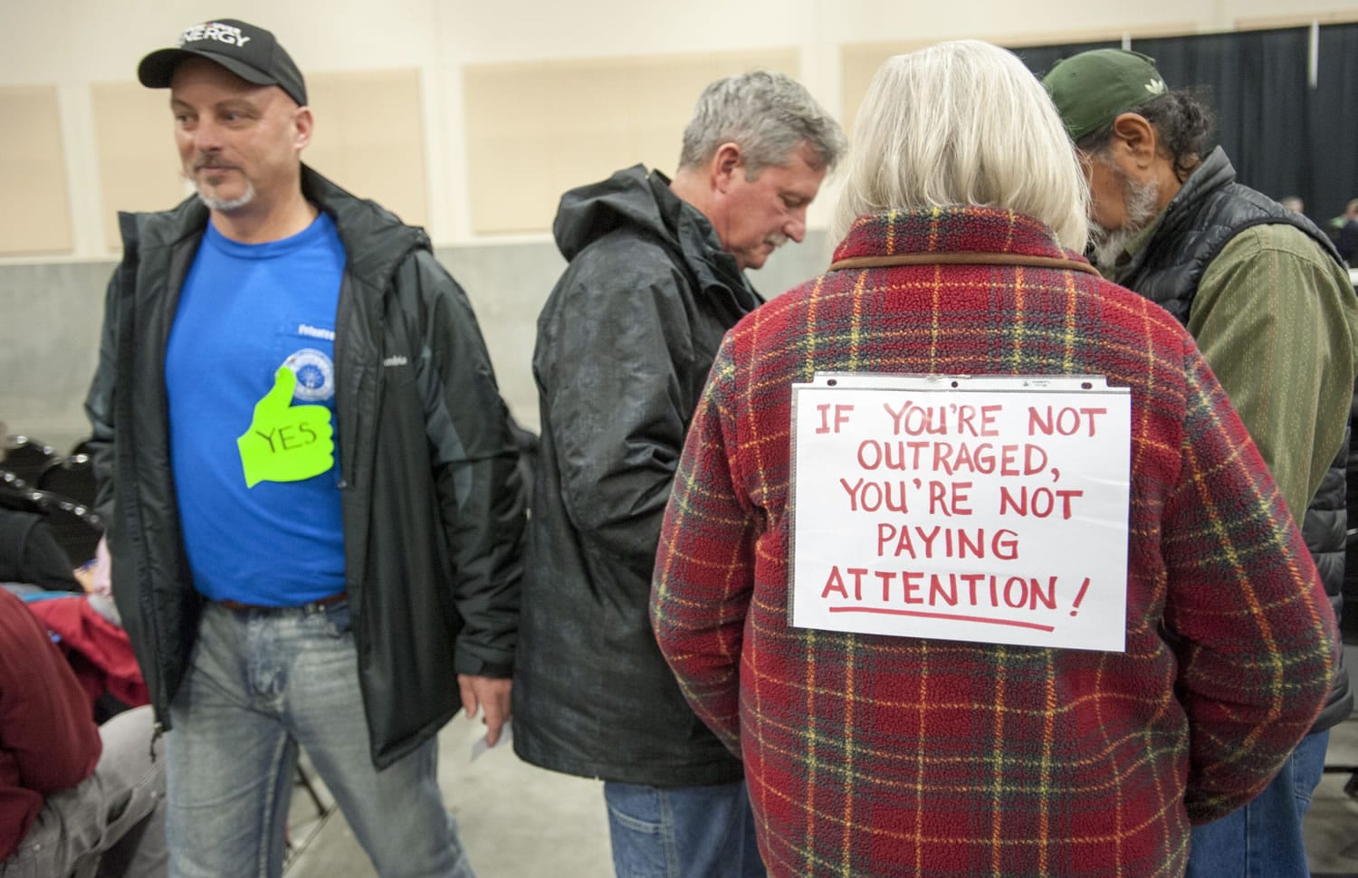 A pro-terminal supporter walks past Edie Cotton, left, who had a sign on her back opposing the terminal, as they attended the Energy Facility Site Evaluation Council&#039;s hearing Jan. 12 in Ridgefield on the construction of an oil terminal in Vancouver.