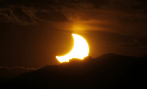 An annular solar eclipse is seen from downtown Denver as the sun sets behind the Rocky Mountains late on Sunday.