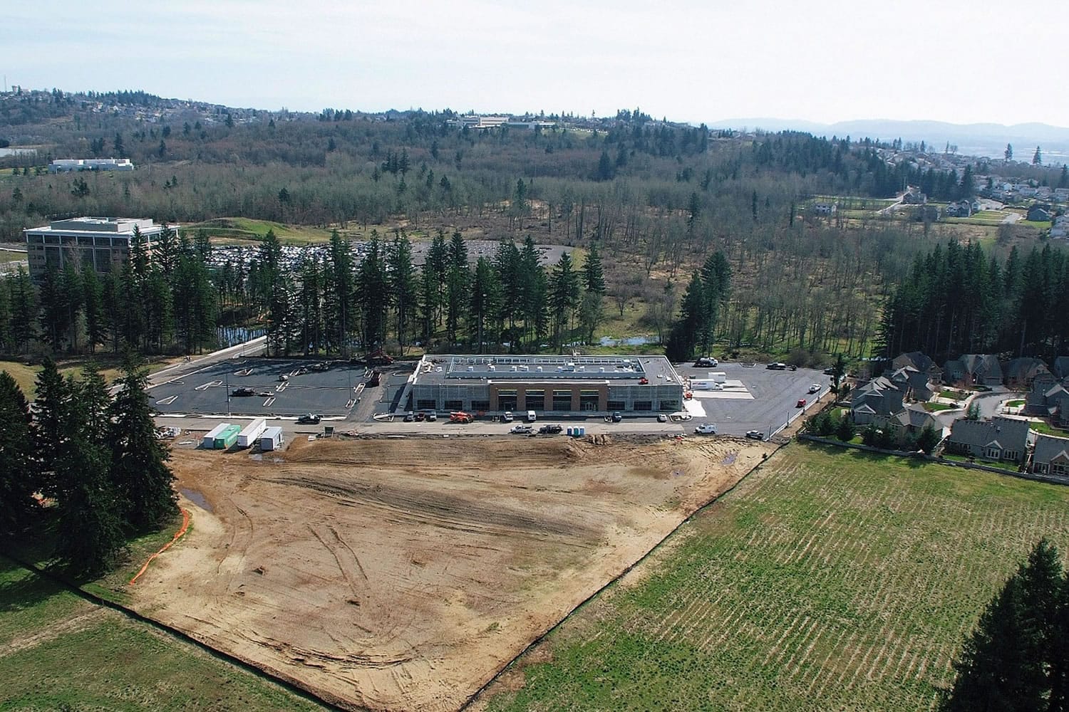 An aerial view of Fisher Investments' Camas campus shows the company's newly completed one-story building with its multistory office building in the background.