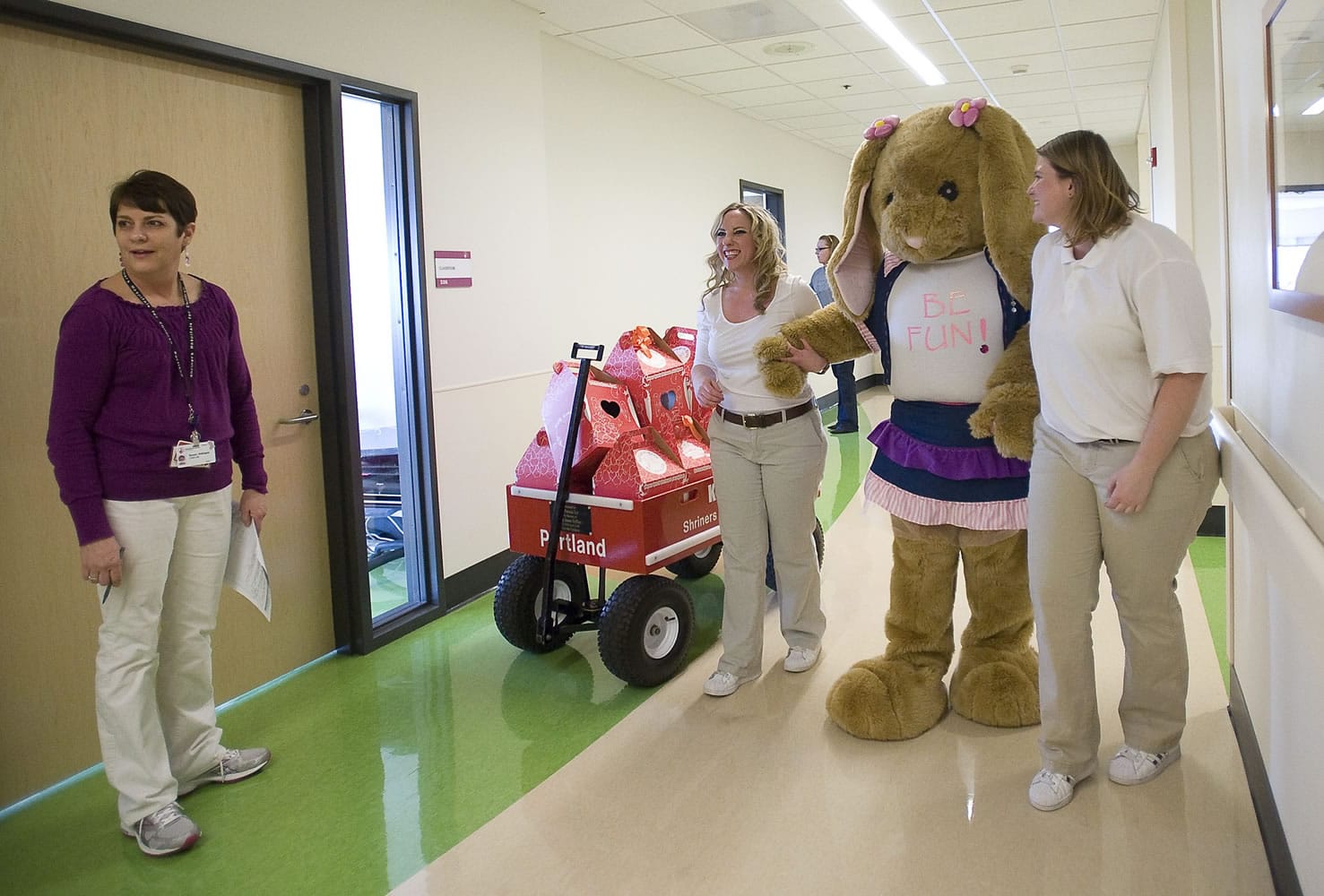 Certified child life specialist Susan Gallegos, from left, looks down the hospital corridor as Build-A-Bear employees Darcy Potter and Shannon Nashis help guide Danielle Thomas, who is dressed in a bunny suit, while visiting patients.