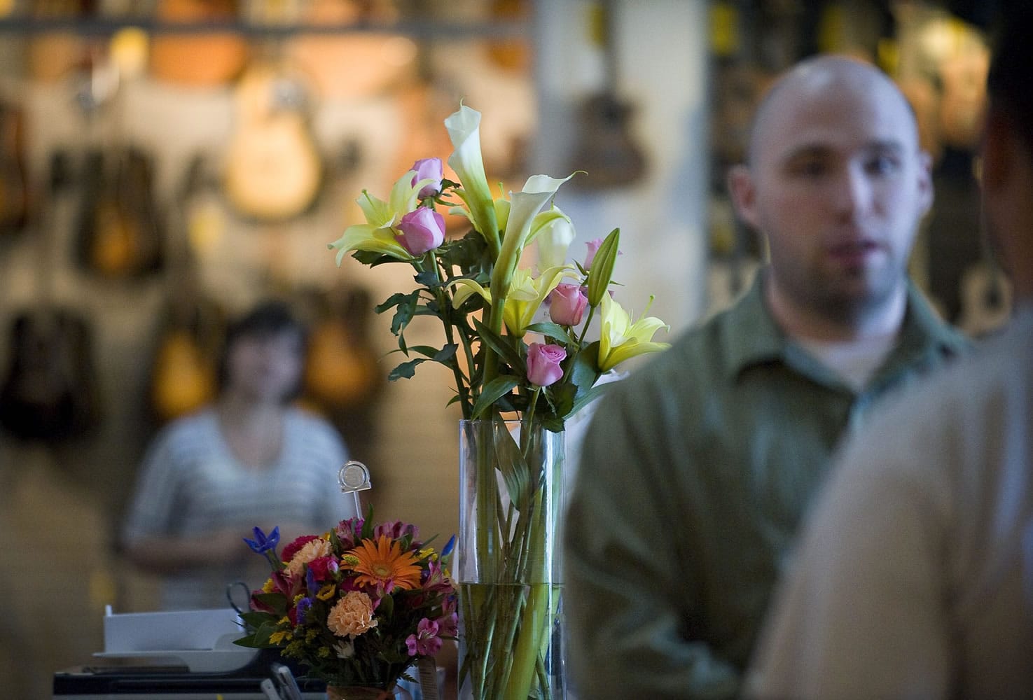 Flowers sit behind the register Friday while sales clerk Ryan Green, right, explains to a customer that Beacock Music Founder Dale Beacock was killed on Thursday in a bicycle accident near Garibaldi, Ore.
