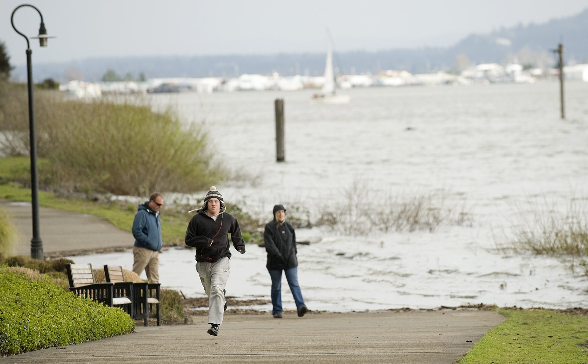 The Columbia River swallows up part of the Waterfront Renaissance Trail as Dave Altman, center, of Vancouver and Greg and Cheryl Fewins of Puyallup navigate around the flooded path on Sunday.