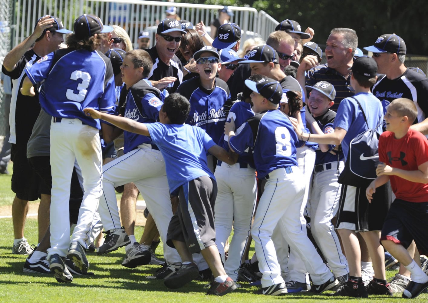 The North Bothell Little League team is surrounded by supporters as they celebrate their 5-3 victory in the championship game against Kent at the Fort Vancouver Little League field on Saturday.