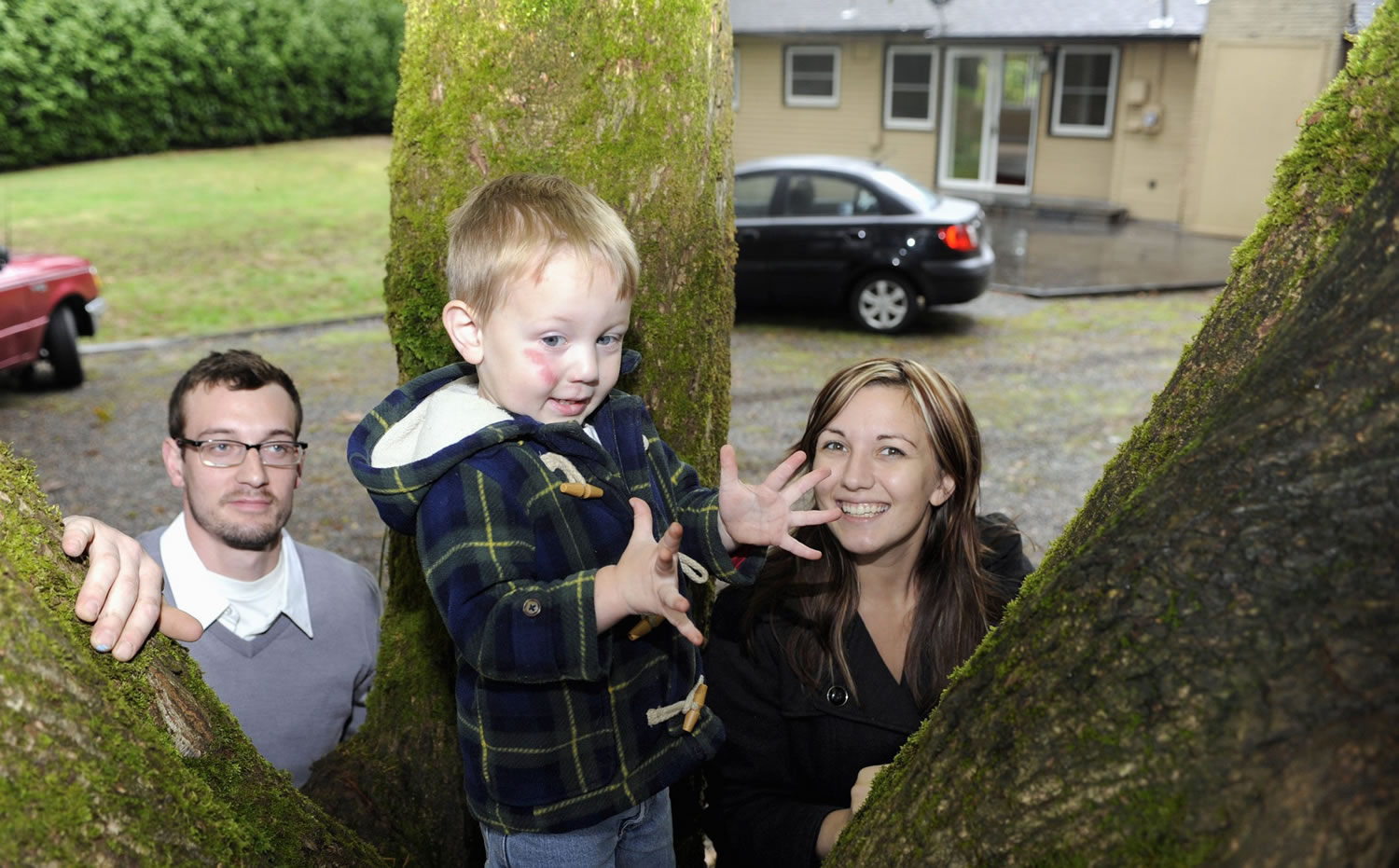 Two-year-old Zephyr Thackeray shows off his new climbing tree with the help of his parents, Ian Thackeray, left, and Tara Thackeray, right, in the back yard of their newly purchased Vancouver starter home.