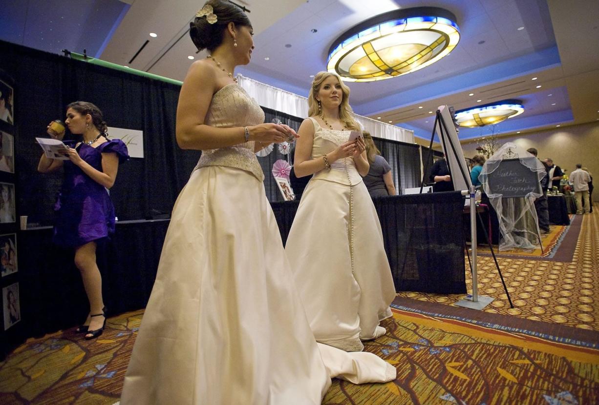 Models, from rear left, Gina Perrone, 28, of Portland; Lacey Koplan, 28, of Vancouver; and makeup artist and model Kendal Moore, 22, of Vancouver, work the booth for AJ's Hair and Makeup at the Marry Me!