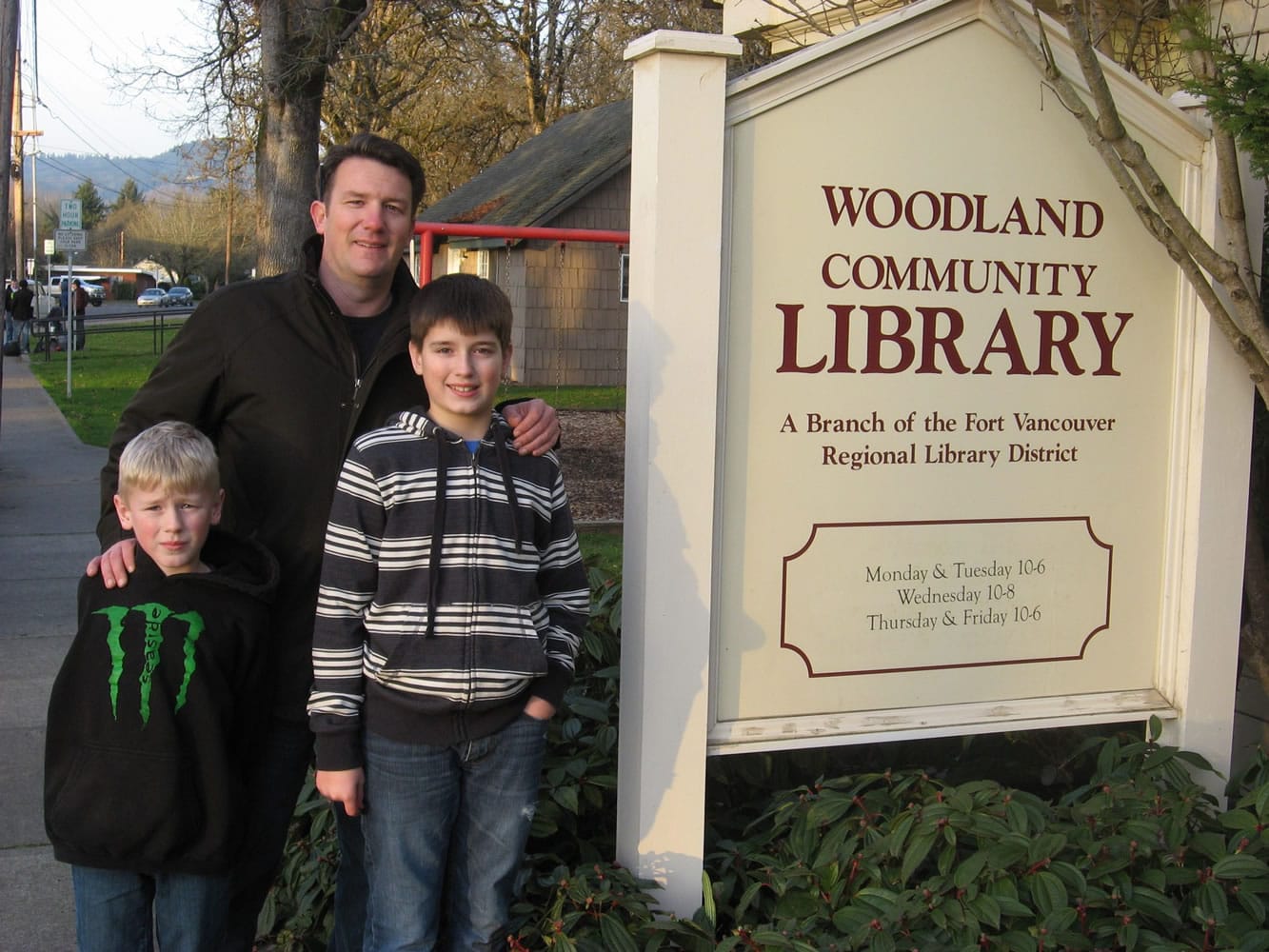 Woodland: Seven-year-old Garrison, from left, father Nick and 12-year-old Austin Massie removed the old and installed new lettering denoting new operating hours on the sign in front of the Woodland Community Library.