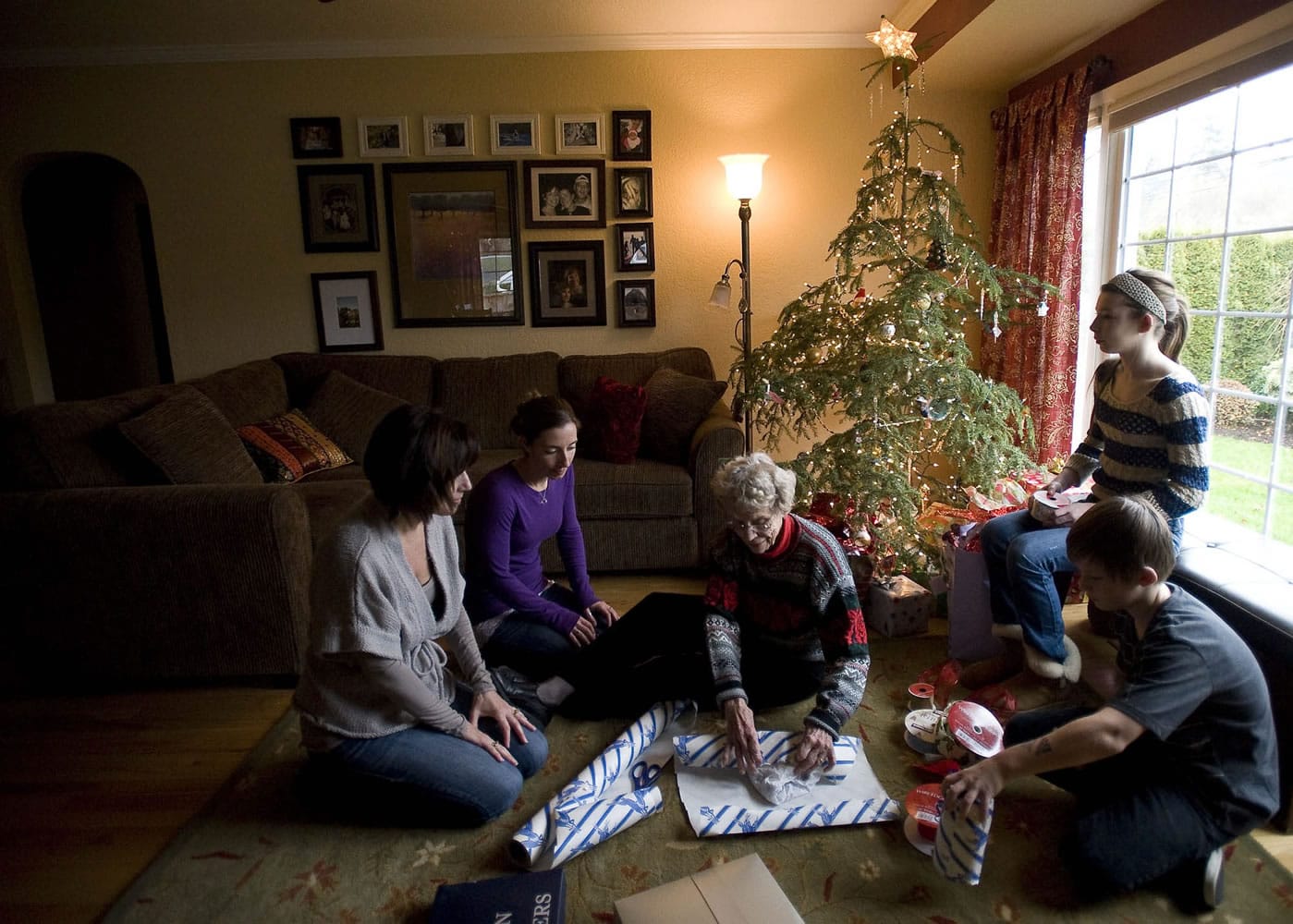 Barbara Joyce Olson, center, wraps gifts with her daughter Carla Munson, left, granddaughter Alaina Munson, second from left, and great-grandchildren Elle Munson, 13, by the window, and Ashton Munson, 11, right.