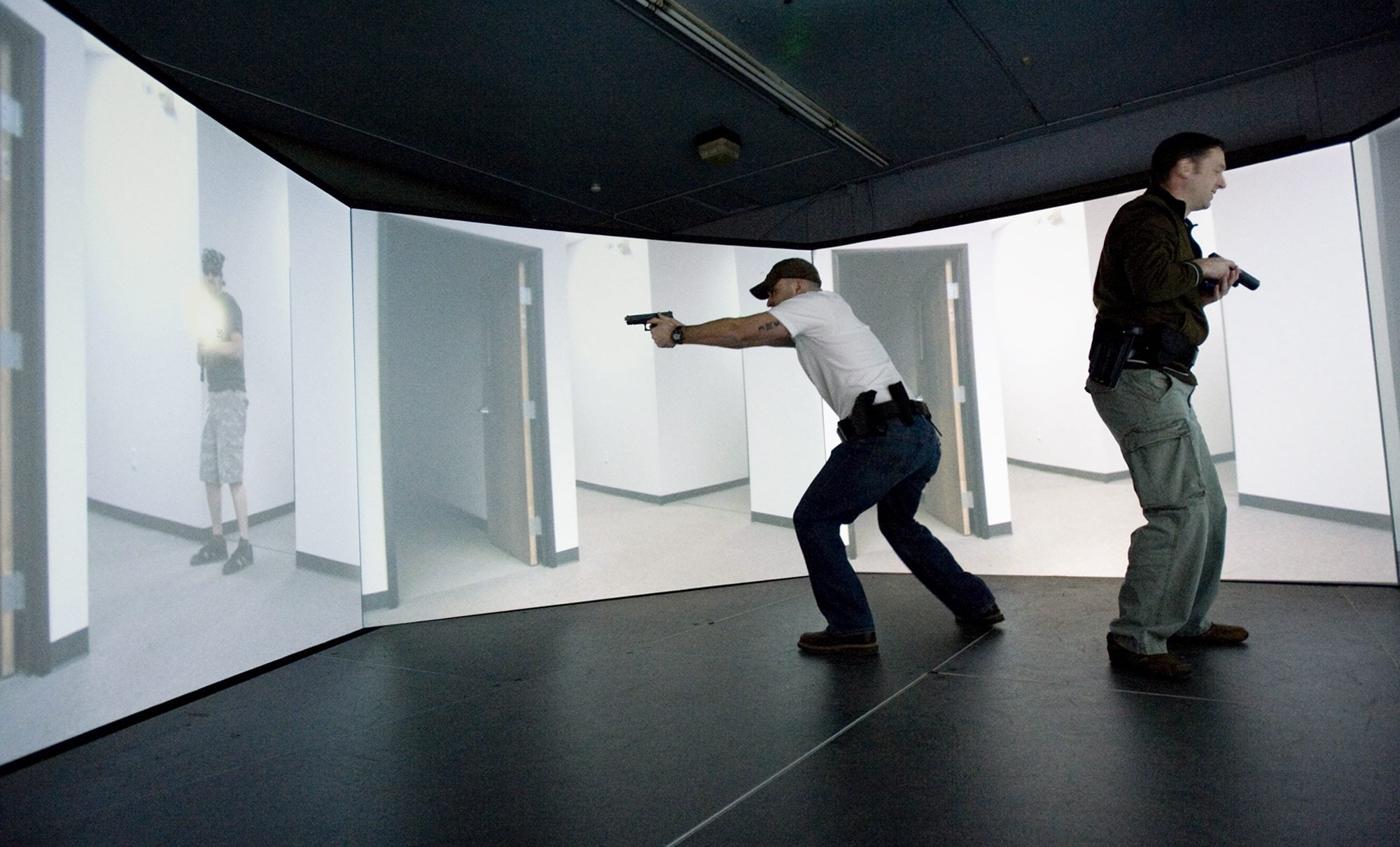 Photos by steven lane/The Columbian
Camas Police officers Henry Scott, left, and Tim Fellows deal with a gunfight  scenario Wednesday inside a five-screen,  300-degree training stage at Threat Dynamics in Tualatin, Ore.