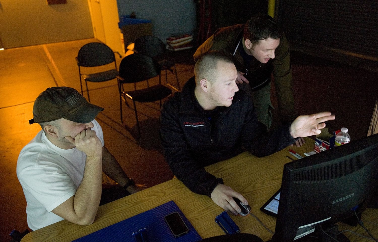After a session, Camas Police officers Henry Scott, left, and Tim Fellows, right, have their performance reviewed by system operator Josh Detar.