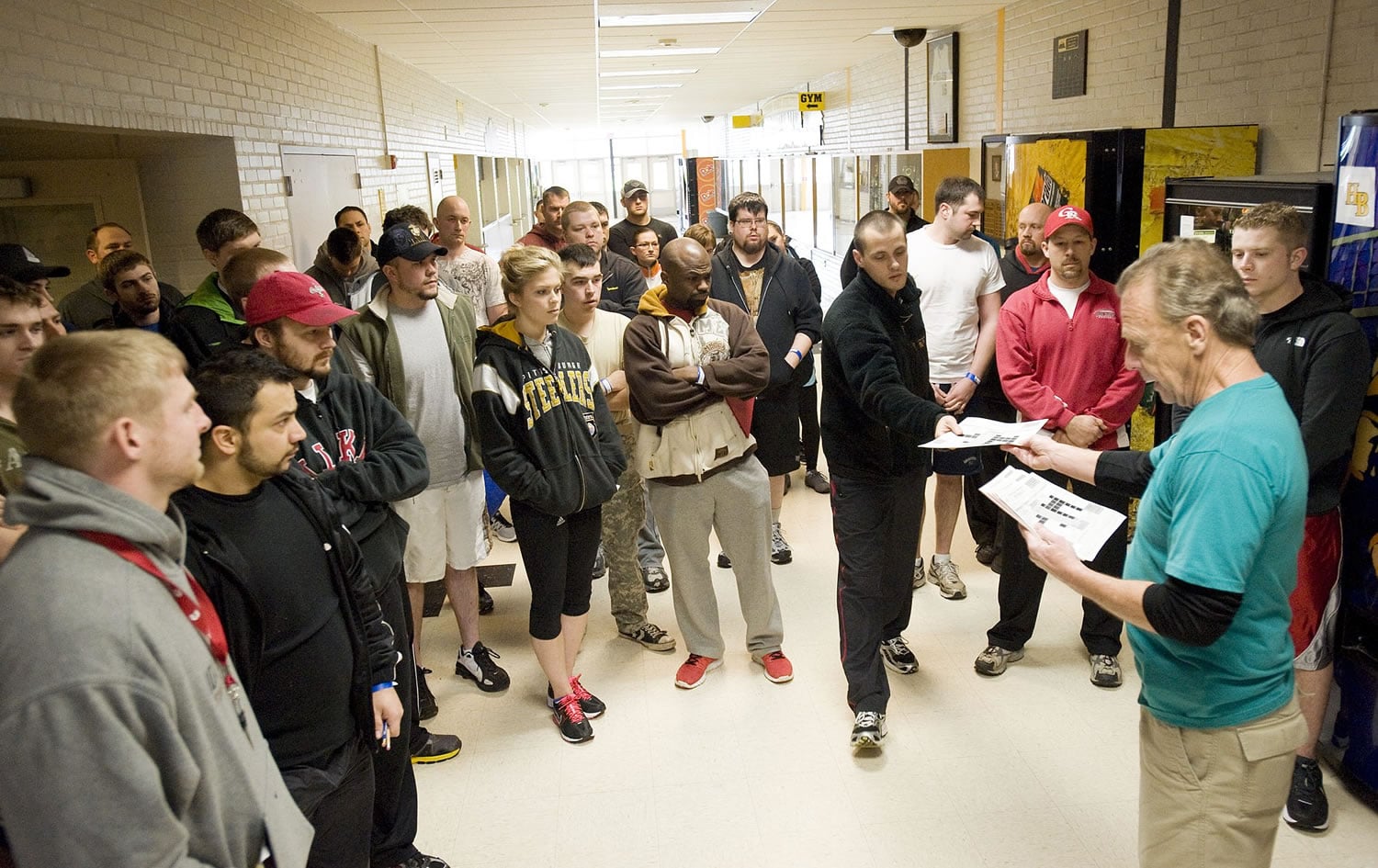 Applicants wait for their names to be called by Public Safety Testing's Bill Curtright, right, to find out if they passed the written portion of their test at Hudson's Bay High School on Feb. 12.