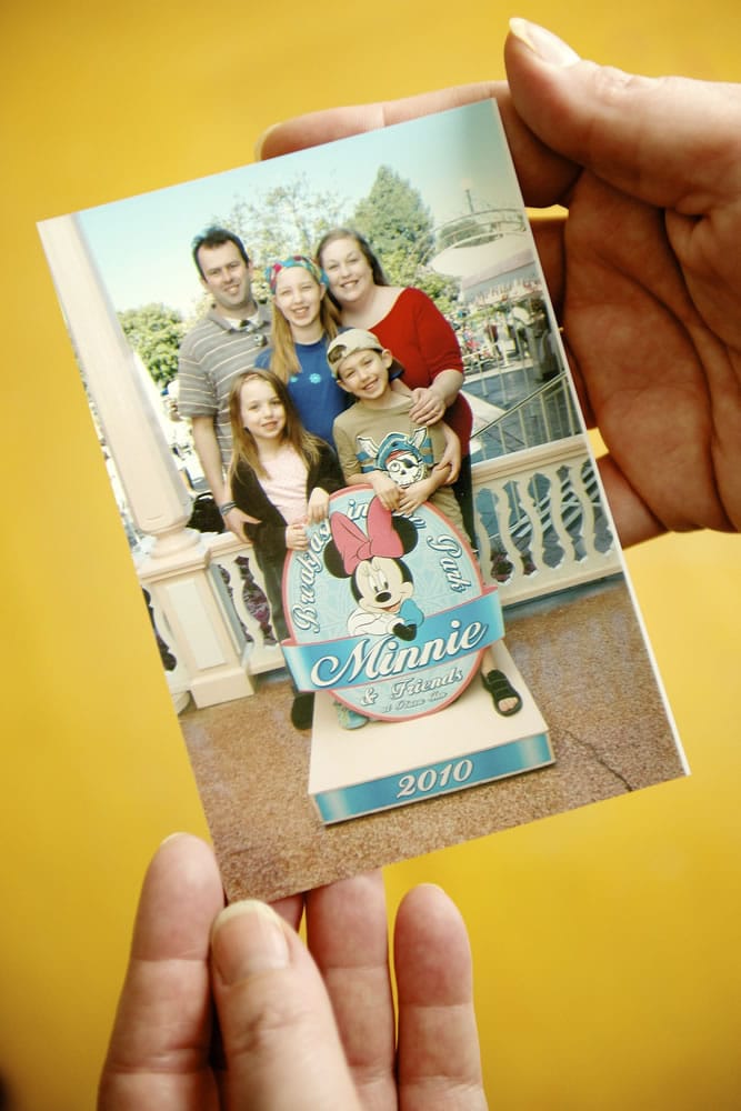 Laina Harris holds a photograph of her family on a vacation to Disneyland.