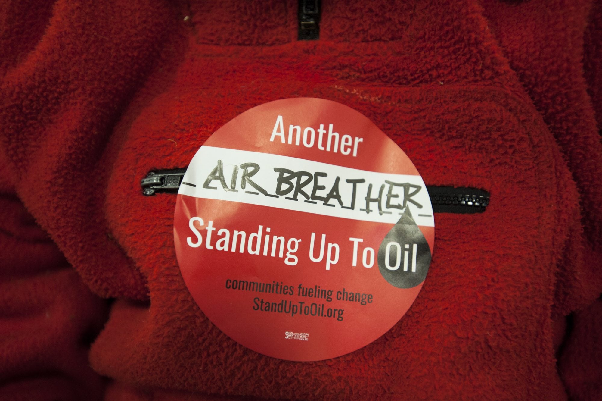 A woman wears a sticker stating "Another air-breather standing up to oil" at a public hearing about a proposed oil transfer terminal in Vancouver January 5, 2016. The hearing is the first of two scheduled by the state Energy Facility Site Evaluation Council, the state regulatory body that is reviewing the project.