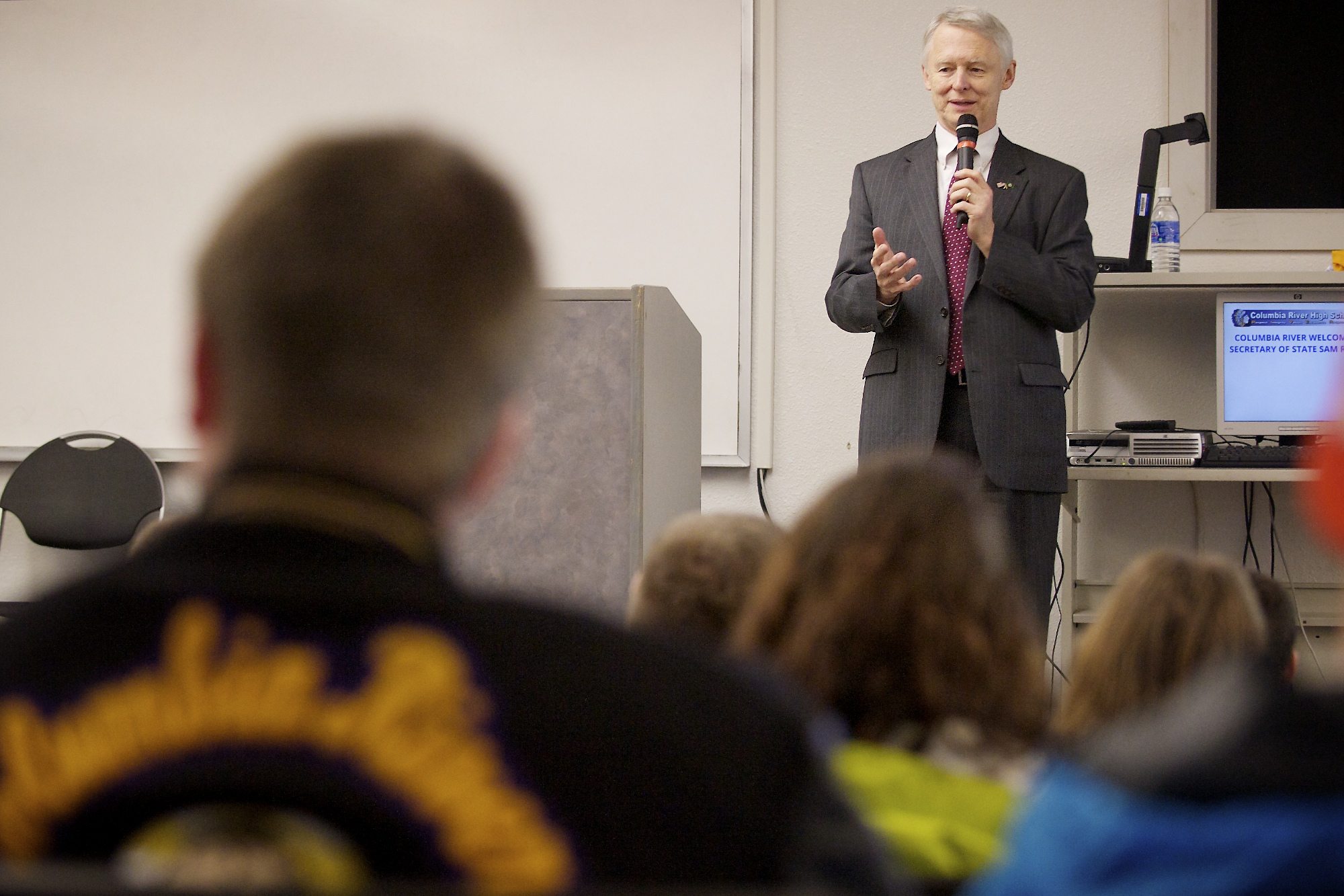 Secretary of State Sam Reed tells Columbia River High School students about the excitement he saw in youths when he observed elections in Russia and Uganda.