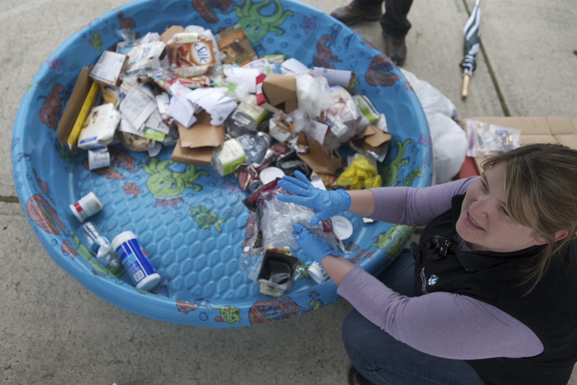 Terra Heilman, waste-reduction specialist with Waste Connections, explains which items are recyclable as she picks through the contents of a family's recycling bin Wednesday at the home of Tracy Davis.