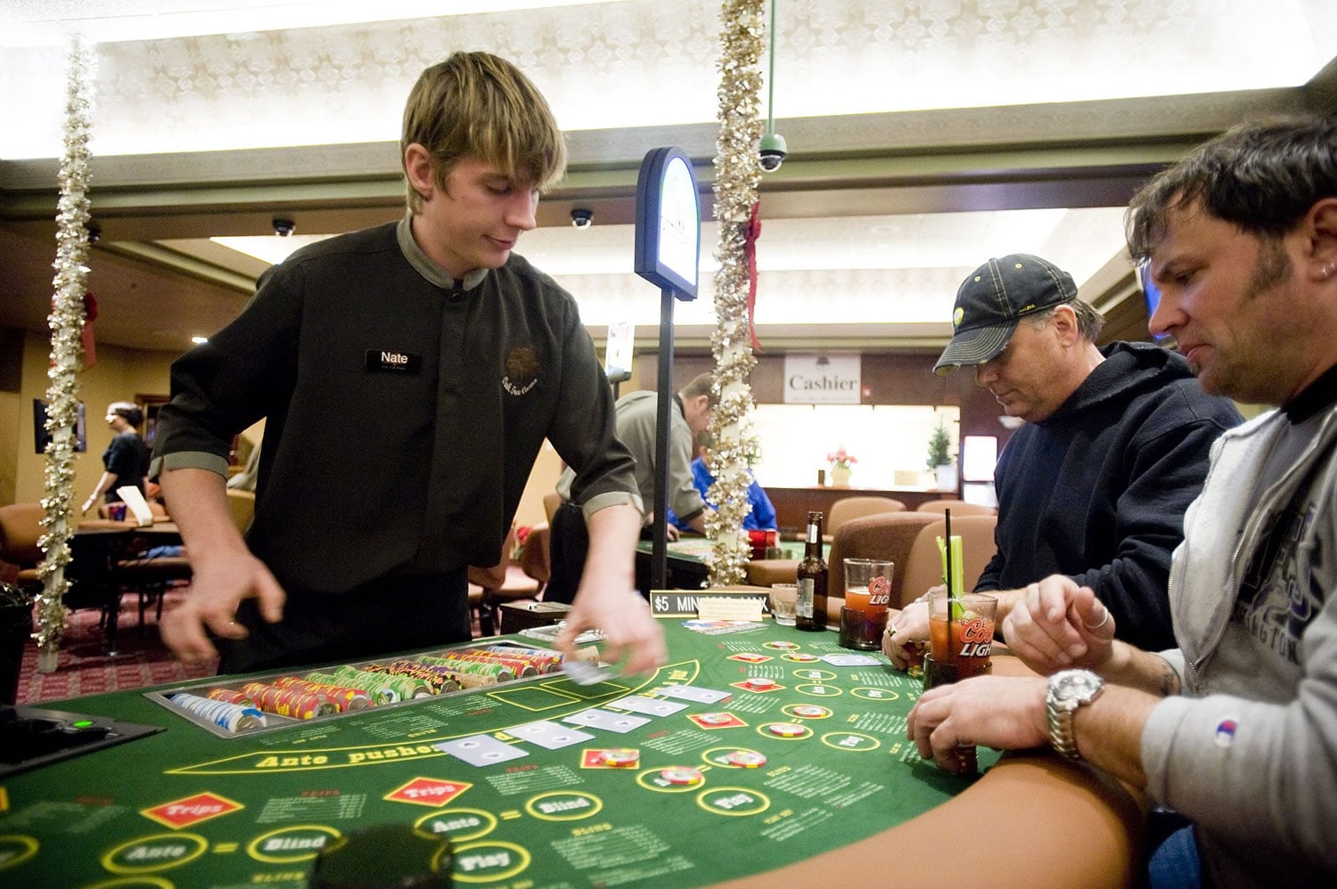 Kevin Hildebrandt, center, and Vaughn Kercher, both from Seattle, play poker at dealer Nate Wheatley's table at the Oak Tree Casino on Saturday, the Woodland card room's opening day.